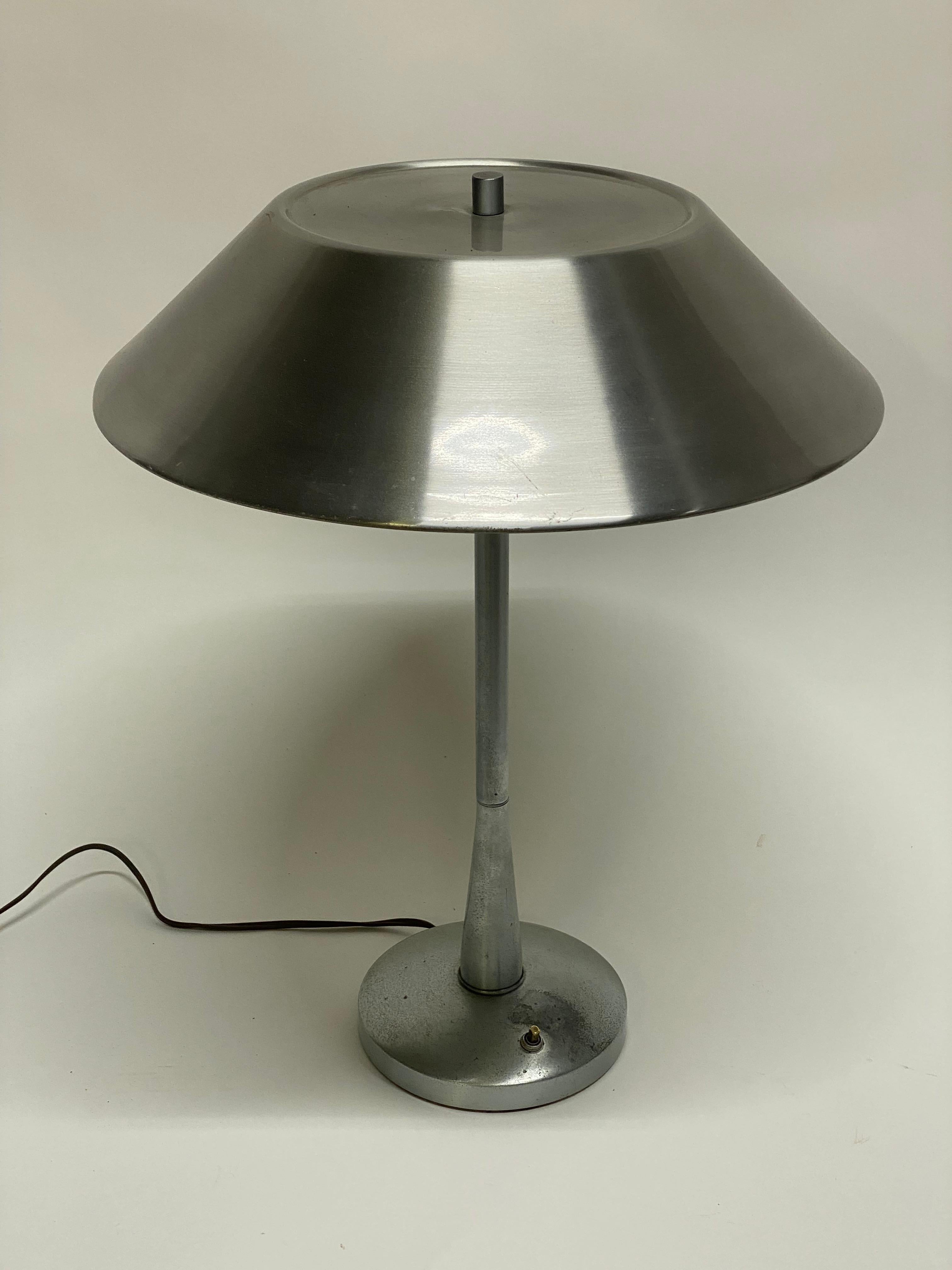 Lampe de table en aluminium Mutual Sunset. Elle est dotée d'une tige effilée, d'un diffuseur de lumière, de doubles douilles et d'un abat-jour en forme de chapeau. Une merveilleuse esthétique de l'âge des machines. Vers 1950. Faible signature sur