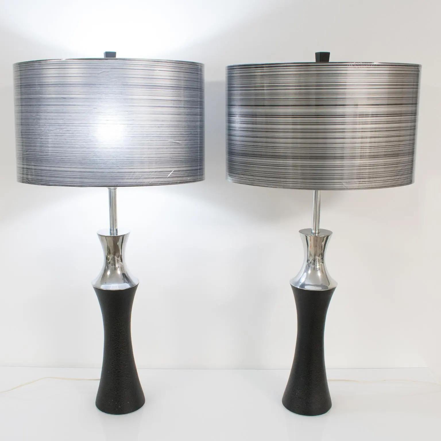 This pair of table lamps, designed by Mutual Sunset Lamp Co, Brooklyn, NY, boasts a modernist Machine Age shape with polished cast aluminum and black painted metal with a textured pattern. They are complimented with modern ovoid rhodoid shades in a