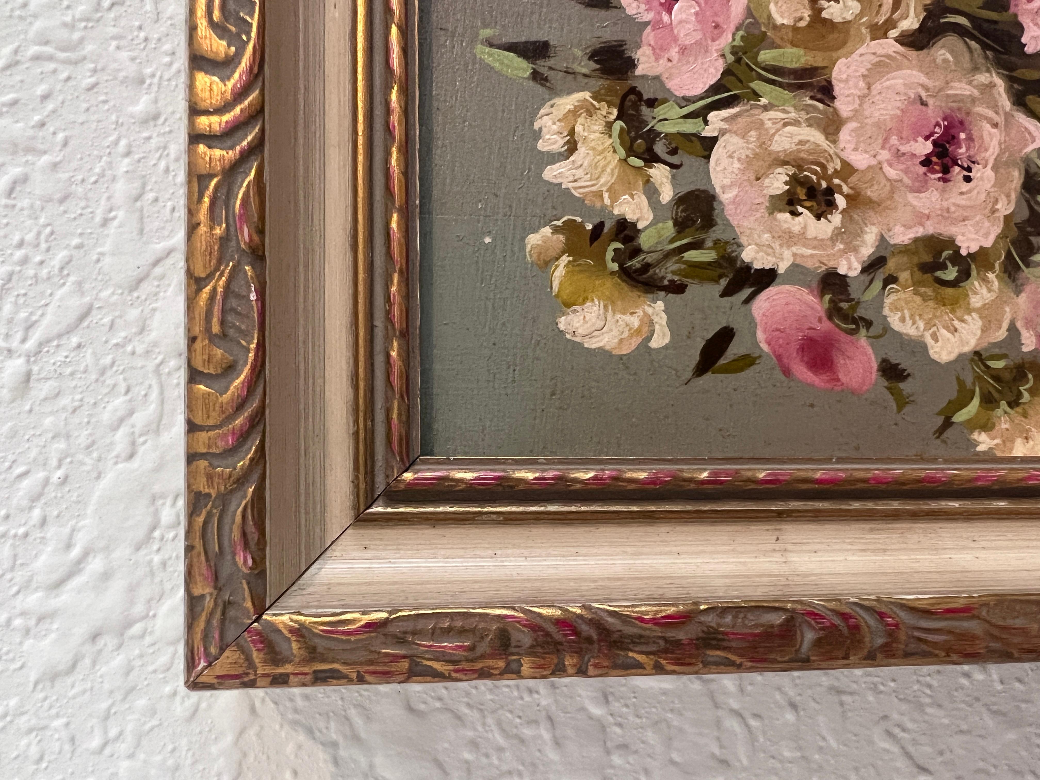 Cette petite peinture à l'huile vintage sur panneau est une charmante nature morte représentant un bouquet de fleurs rose tendre et crème disposées dans un élégant vase aux tons sombres. L'artiste, qui a signé 