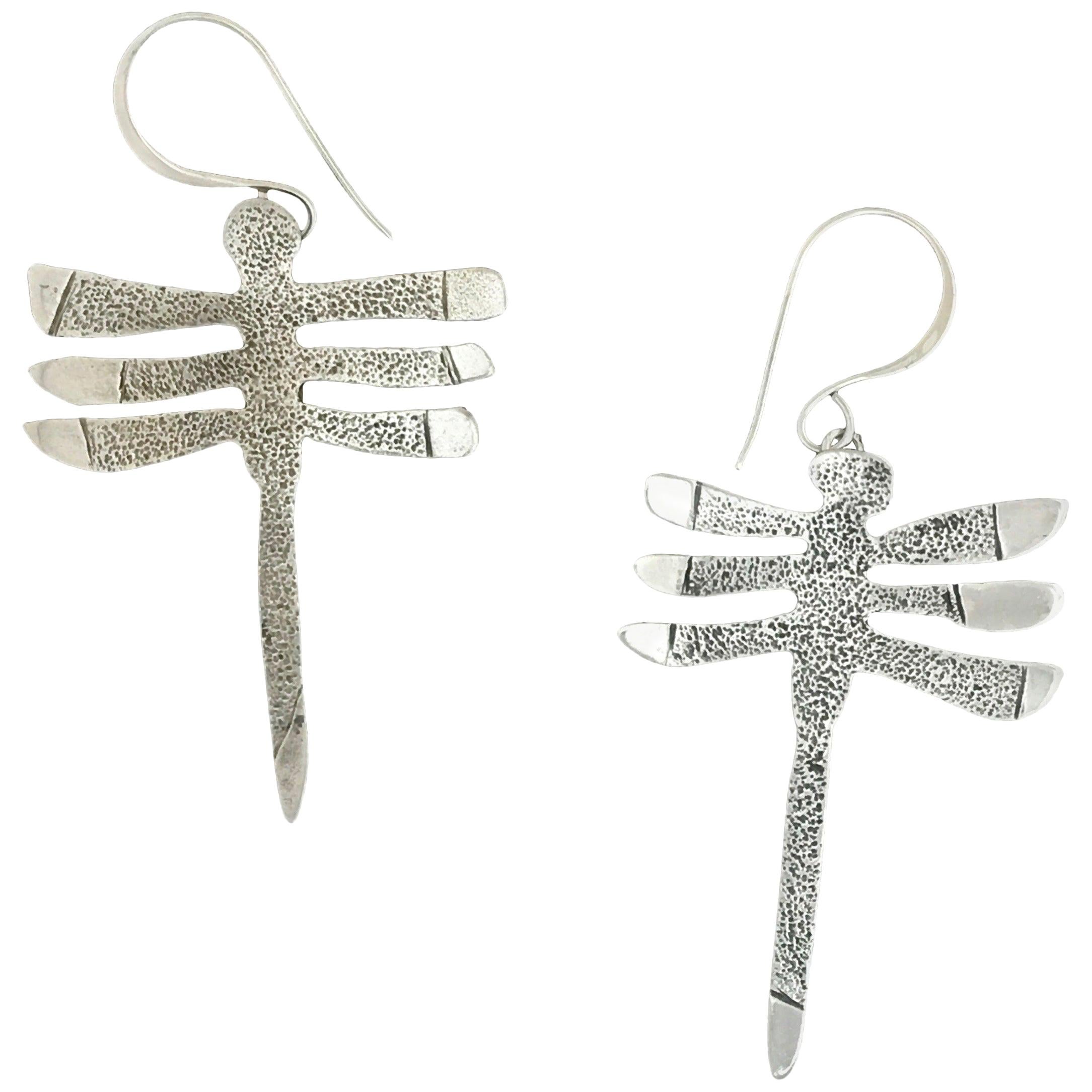 My Protectors, three-winged dragonfly earrings silver Navajo Melanie Yazzie

Melanie A. Yazzie (Navajo-Diné) is a highly regarded multimedia artist known for her printmaking, paintings, sculpture, and jewelry designs.

She has exhibited, lectured,