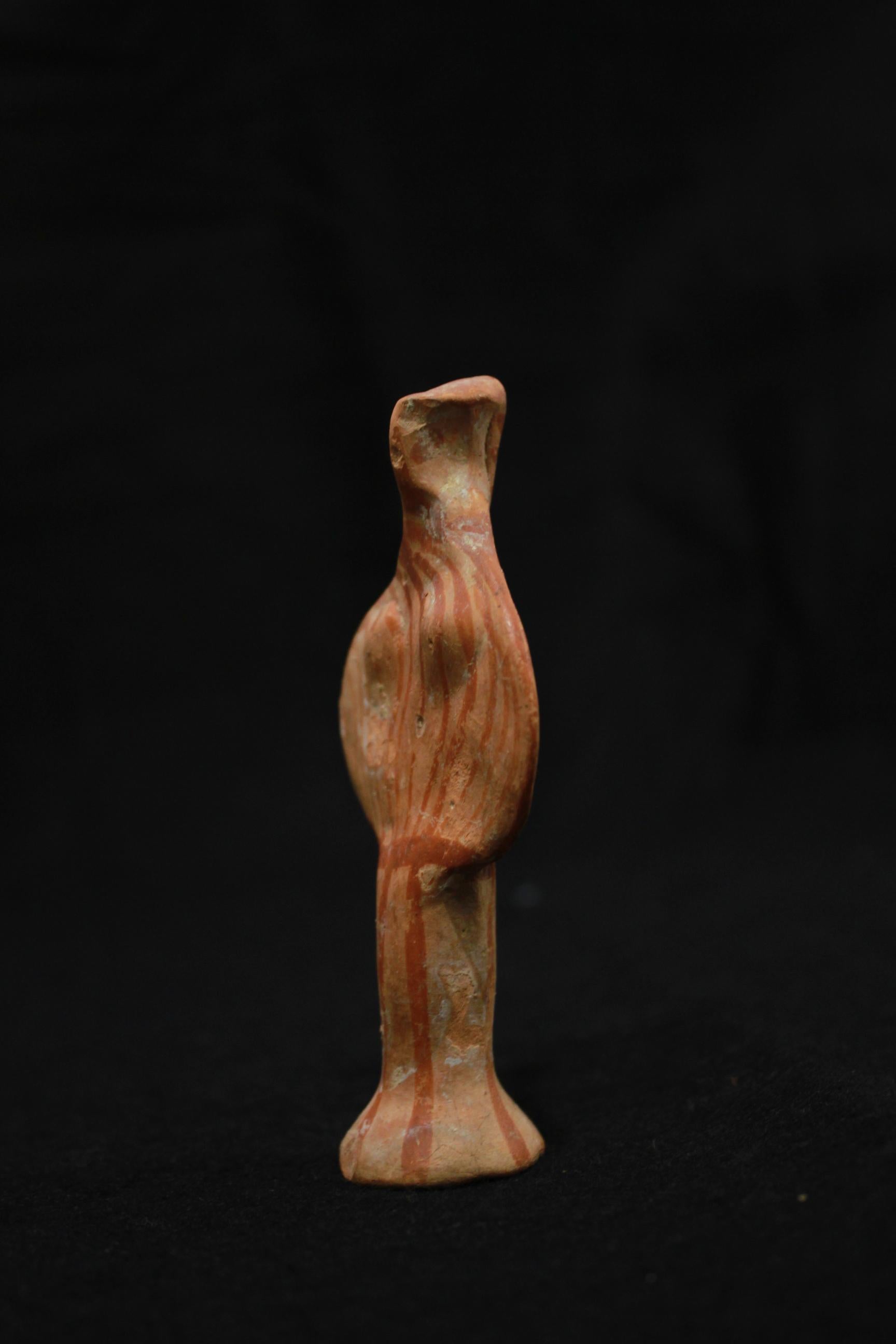 Feminine statuette with aviary traits and stylized forms. The pointed face was made by pinching the clay between two fingers. Her arms and her bust are disc shaped. Her breasts are slightly modeled, as is her hair, which is brought back in a long