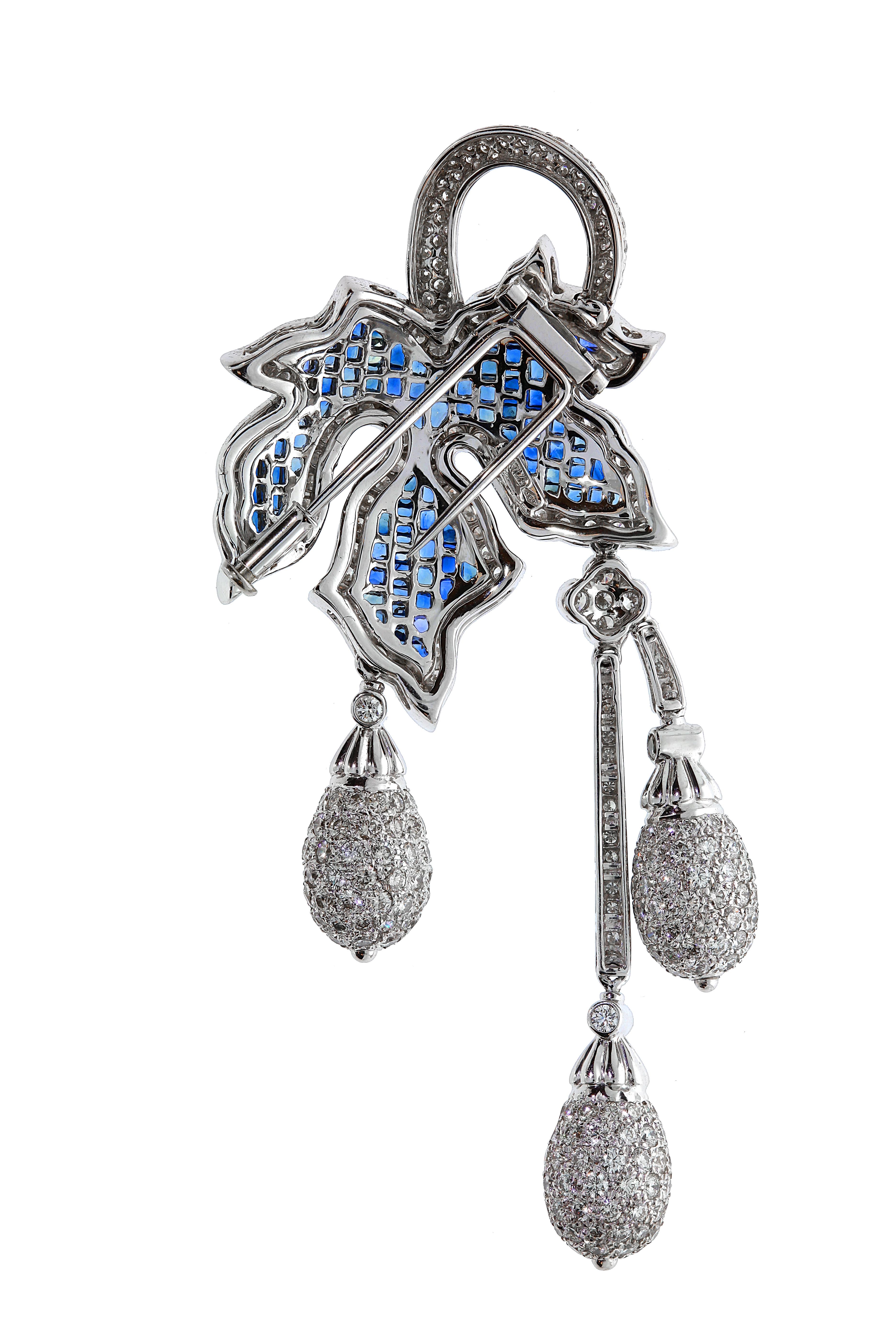 Chatila 18 carat white gold mystery set blue sapphire brooch with a diamond border and 3 teardrop clusters dangling at different heights. A perfectly balanced mixture of traditional and modern.

Details:

-399 diamonds with a total weight of 8.82