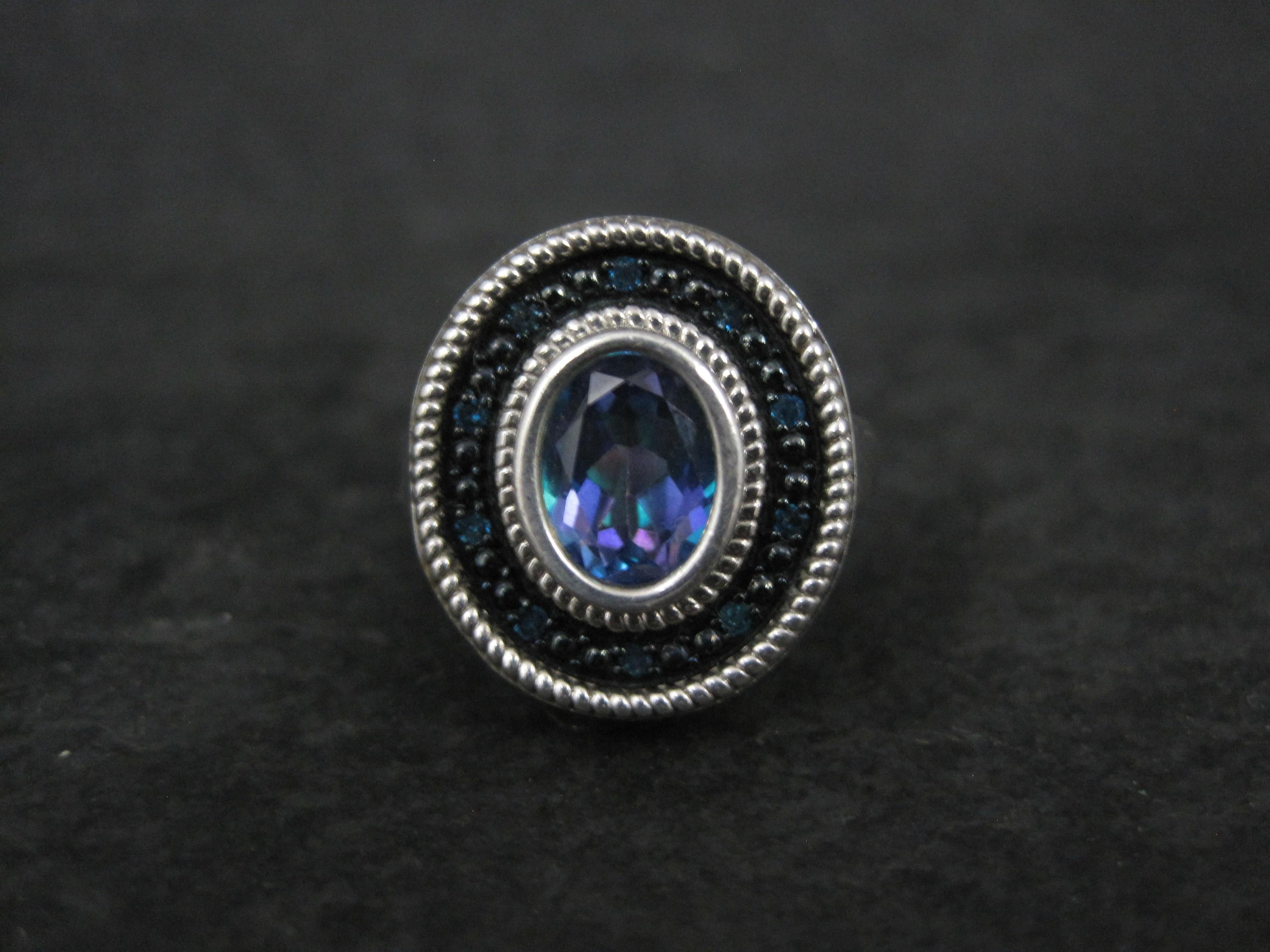 Cette magnifique bague est en argent sterling.
Elle est ornée d'une topaze mystique bleue ovale de 8x6 mm, rehaussée de 10 diamants bleus.

La face de cette bague mesure 1,5 cm du nord au sud, avec une hauteur de 8 mm par rapport au doigt.
Taille : 6