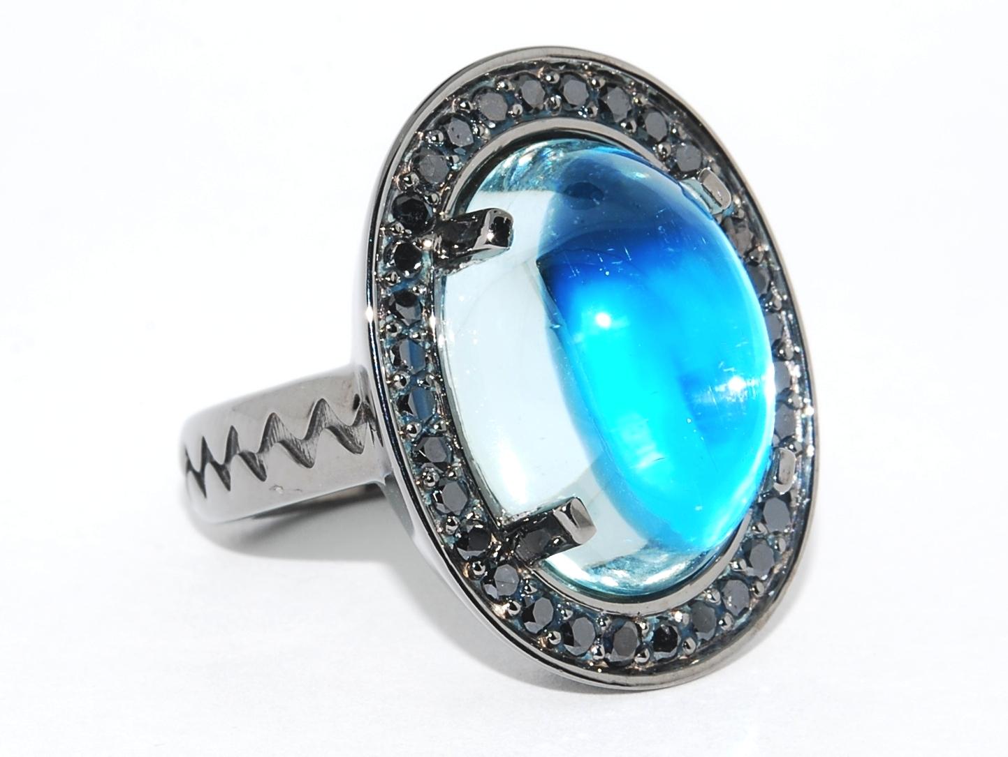 Large oval cabochon Aquamarine set in 17.6 grams of blackened white gold (black rhodium) and surrounded in a halo of black diamonds that have a total carat weight of 0.64 carats. The Aqua measures 17.57 x 12.66.  This is a one of one - and one of a