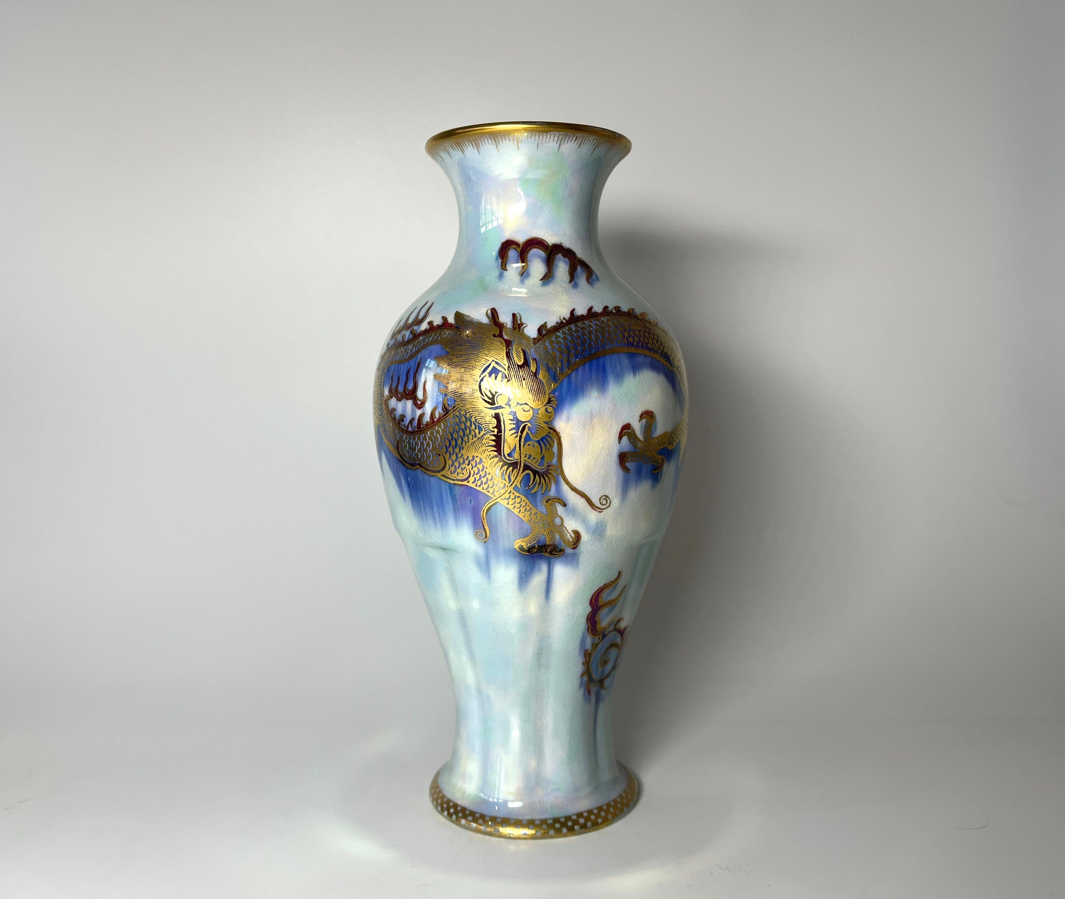 A dramatic blue pearl lustre dragon porcelain vase created in the 1920s by Daisy Makeig-Jones for Wedgwood,
Dominated by a bold gilded dragon on an azure blue background. Exotic gilded script motifs decorate among the pale blue lustre mottling.