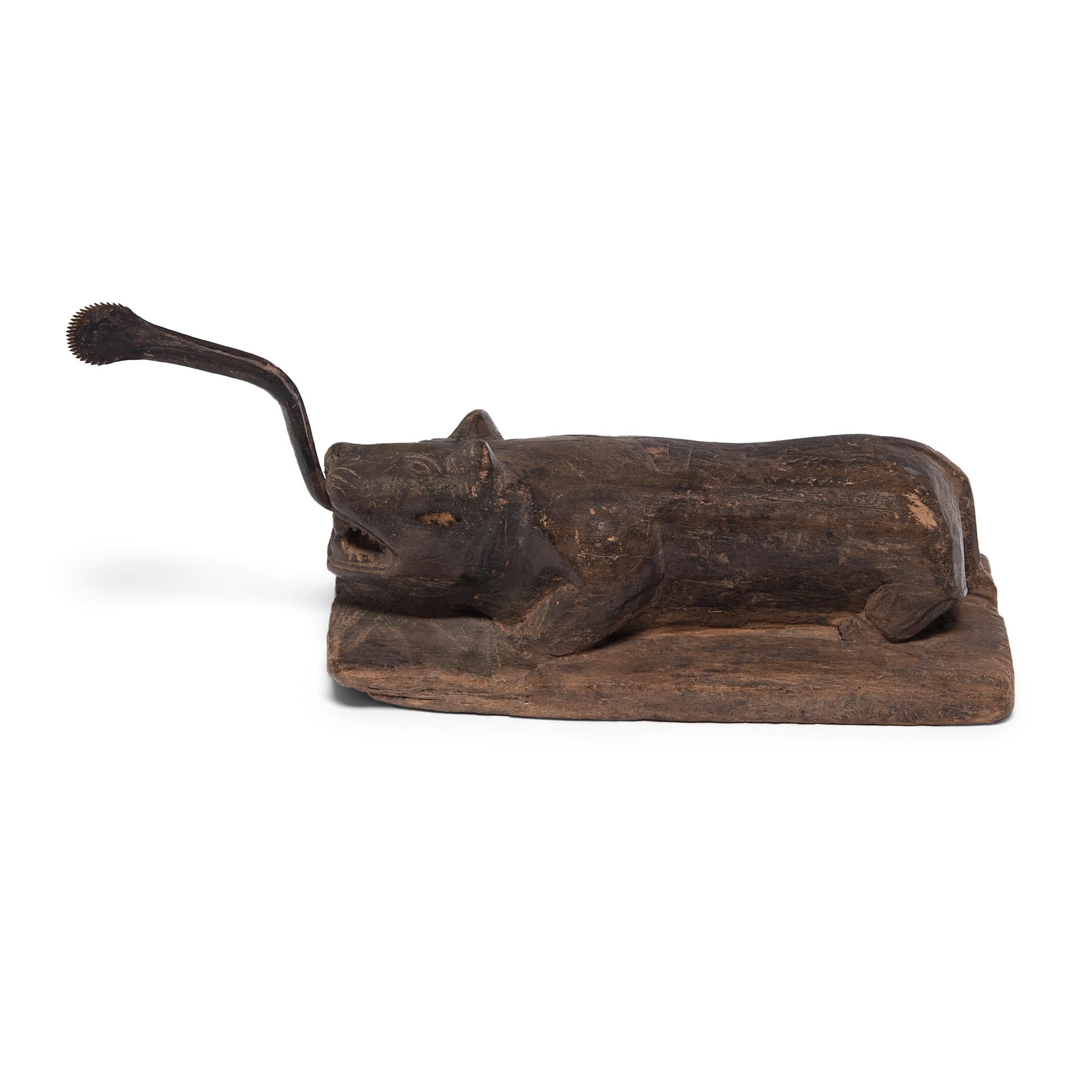 This sculptural early 20th century coconut splitter was carved into the form of a crouching beast ready to pounce. It was likely a merchant's tool in a Southeast Asian market used to split coconuts which were then ground into fine snow-like flakes