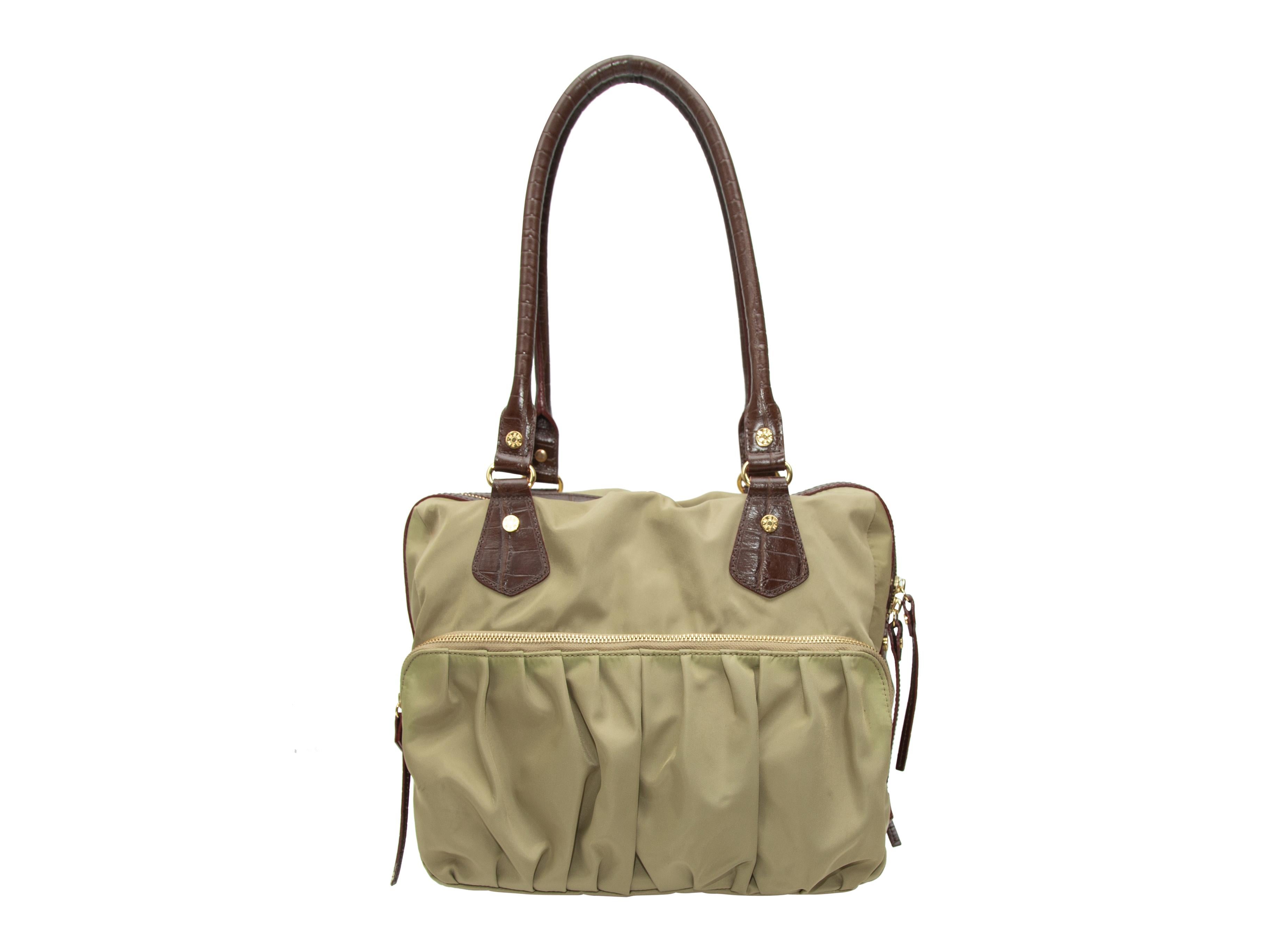 Product details: Khaki nylon tote bag by MZ Wallace. Brown leather trim throughout. Dual zip closure pockets at front. Dual rolled top handles. Zip closure at top. 12