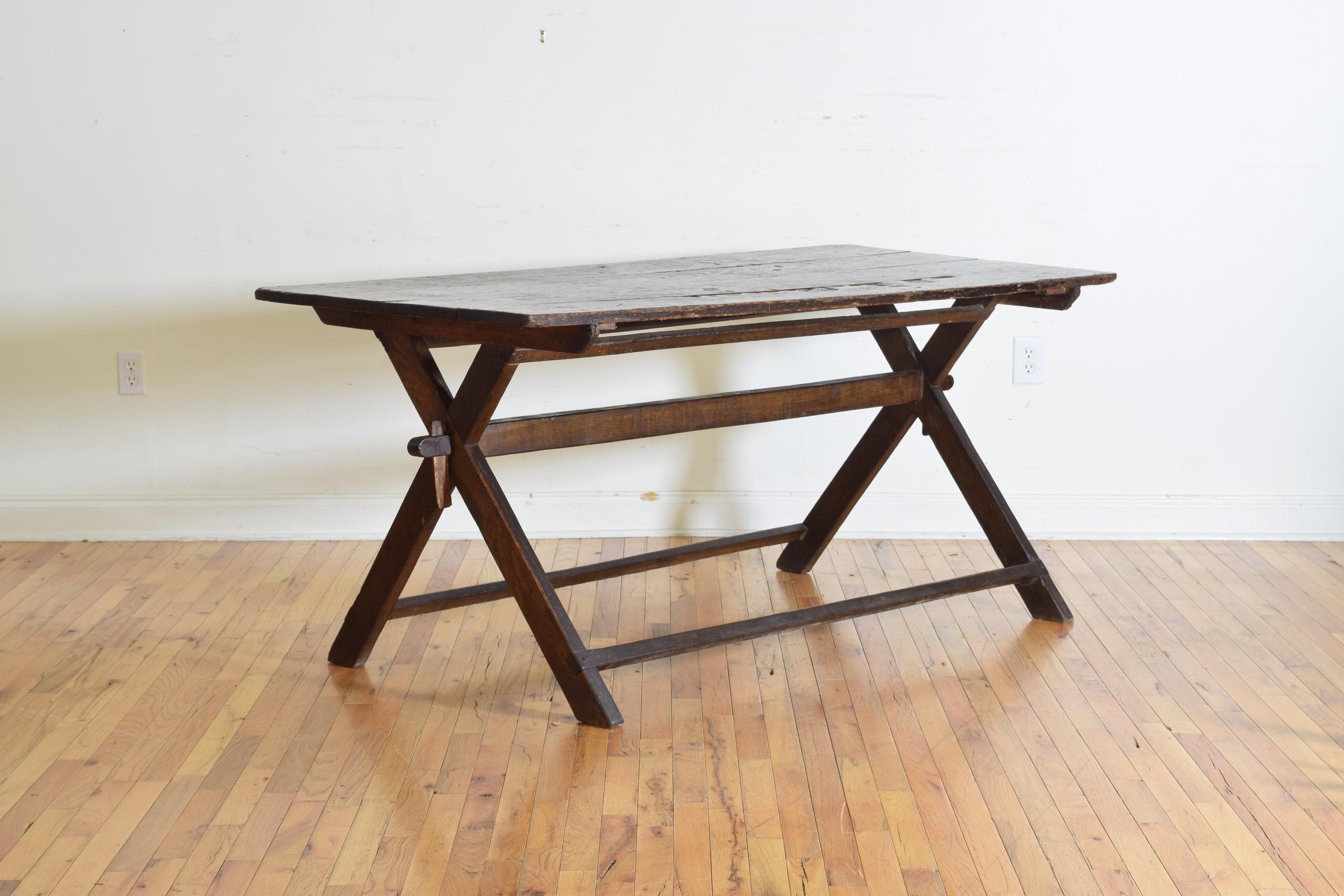 Having a four board top that sits atop an X-form trestle base with double horizontal stretchers, in very solid condition the top with some losses and indentations.