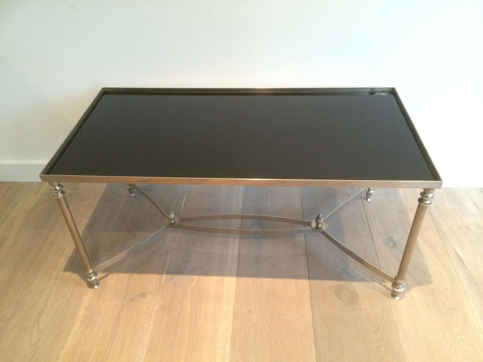 This neoclassical coffee table is made of silver plated metal with a black lacquered glass top. This is a French work in the style of Maison Jansen, circa 1940.