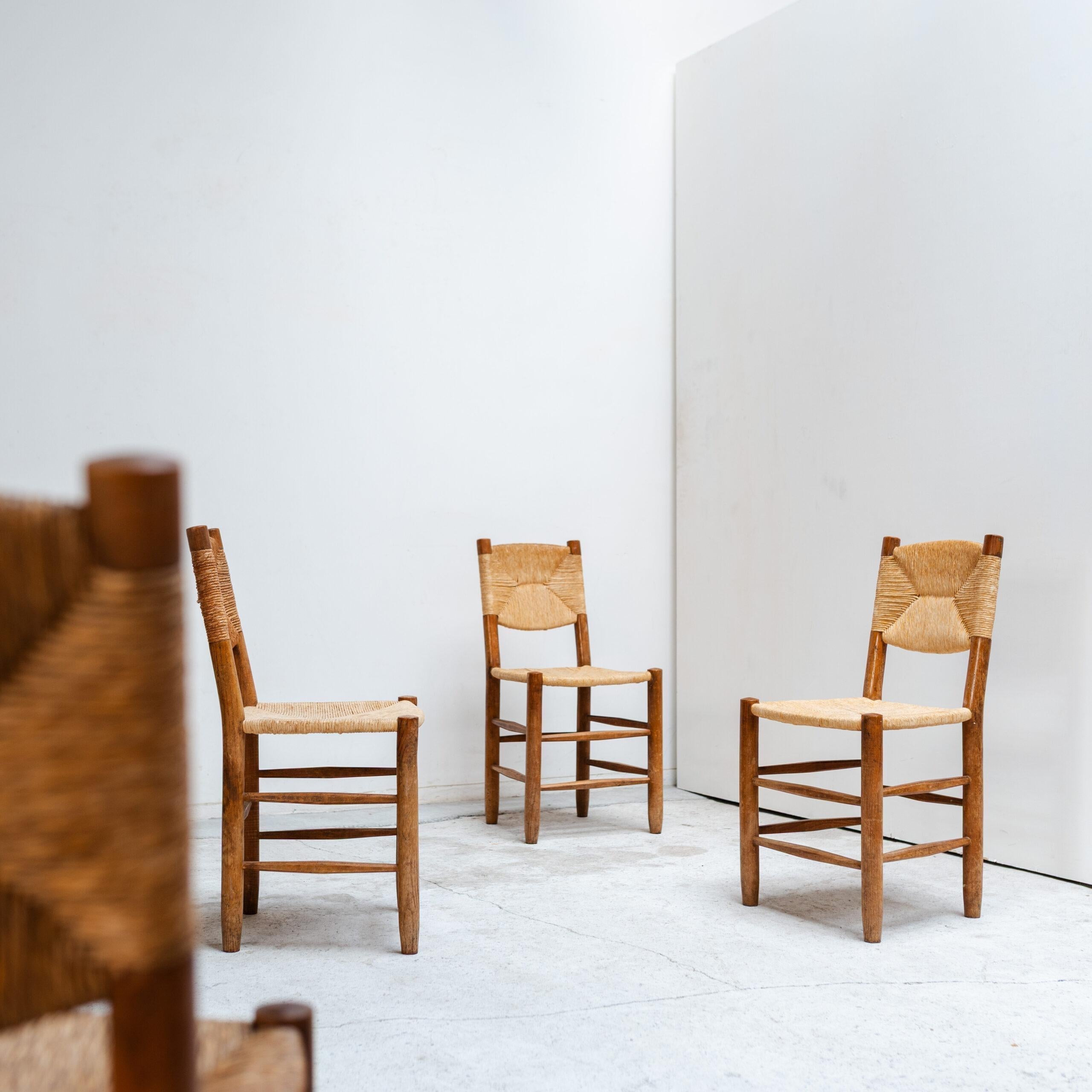 Ensemble de quatre chaises Bauche N°19 dessinées par Charlotte Perriand et produites par Sentou. Caractérisées par leur structure en bois massif et leur assise en jonc tressé à la main, ces chaises incarnent la vision de Perriand en matière de