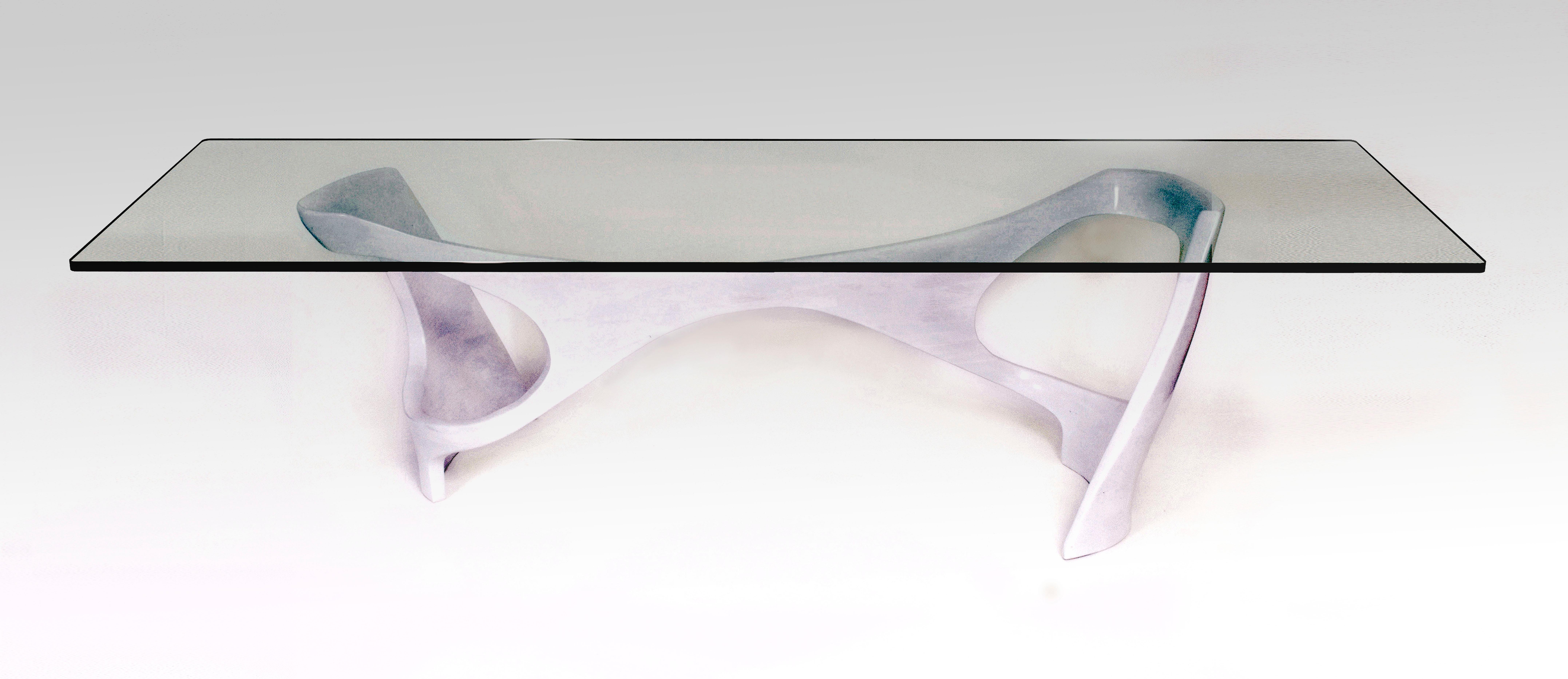 The N2 dining table features a minimal, serpentine base supporting a thick, glass top with 1