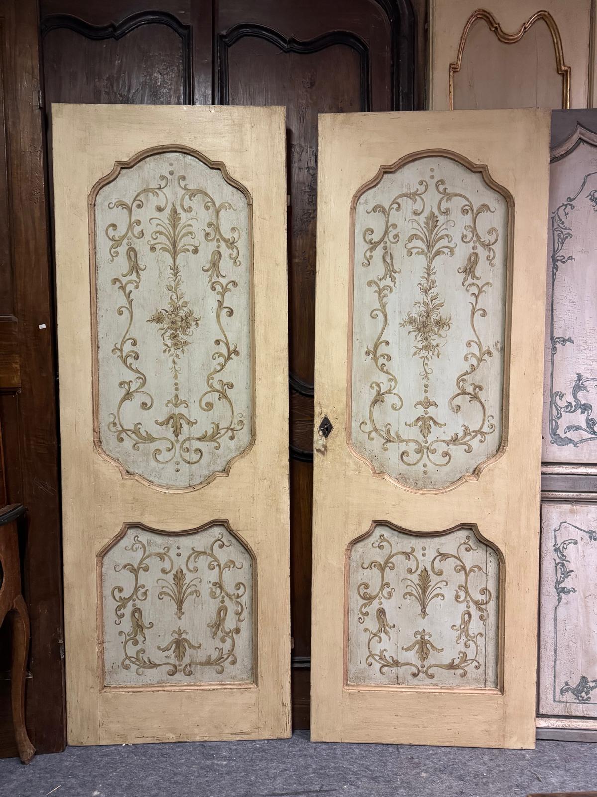 N.2 puertas antiguas idénticas, de madera maciza pintadas a mano y con una hoja, tienen dos paneles ondulados con decoraciones florales y de hojas pintadas, fondo beige amarillento, sin marco y originales del siglo XVIII. Dorso liso con marcos