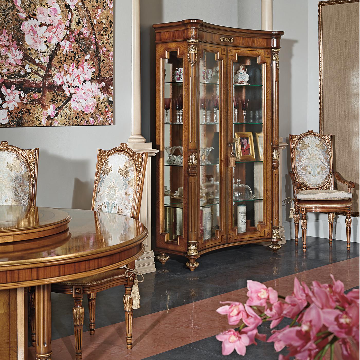 The preciousness of woodworking techniques meets the opulence of Baroque style. This exclusive display cabinet closed by two glass doors flaunts a bold wooden stucture veneered in a combination of rosewood, walnut briar, and feathered ash that is