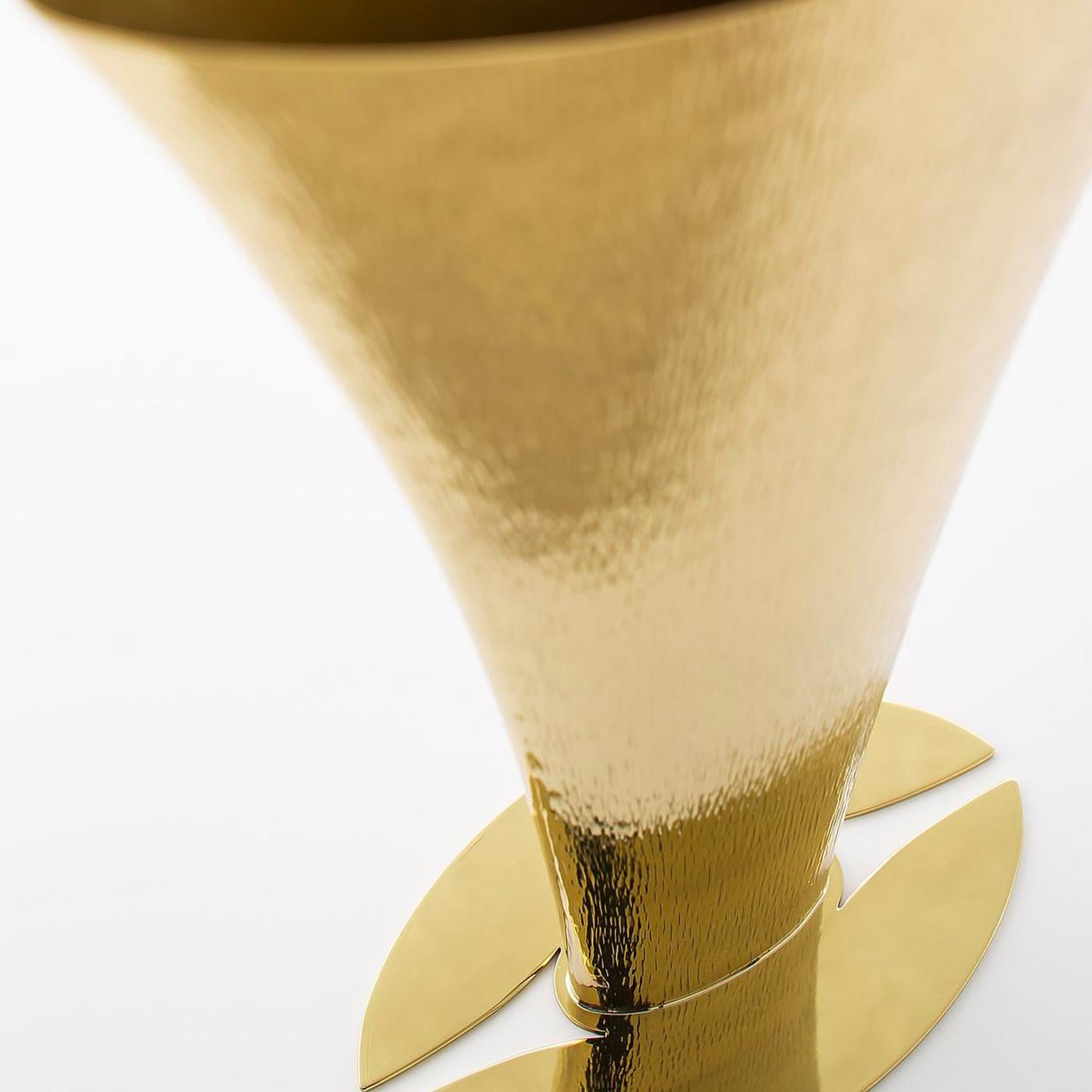 The lengthy heating process of this vase's brass creates its distinct shape while successive rounds of hammering elaborately decorate the exterior. The flared shape rests on a hand-modeled base. Polished and varnished with a special protective