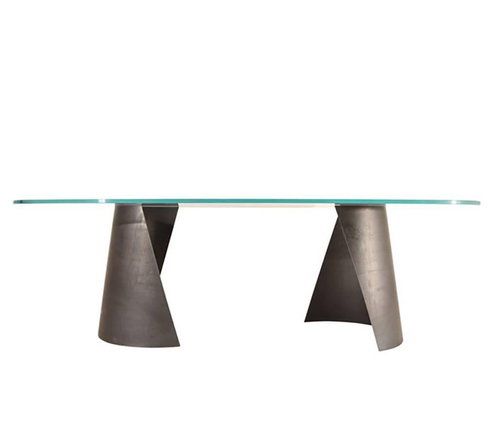Nada Debs modern Serra dining table, blackened steel base, glass top. Inspired by sculptor Richard Serra, the Serra dining table creates a unique impression from every angle. The expressive lines of its manually bent steel base are showcased via an