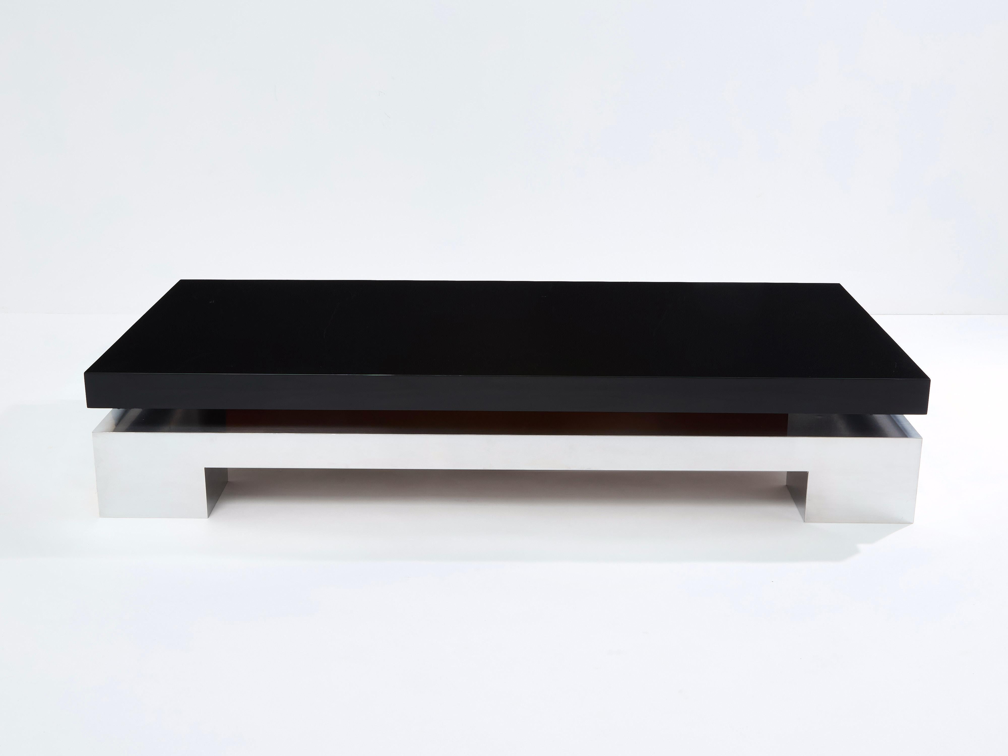 Conçue par Nadine Charteret pour Edition Interieurs Contemporains en 1972, cette grande table basse se caractérise par des pieds robustes et volumineux en acier brossé, avec un plateau laqué noir. Sa symétrie et sa conception architecturale forte se