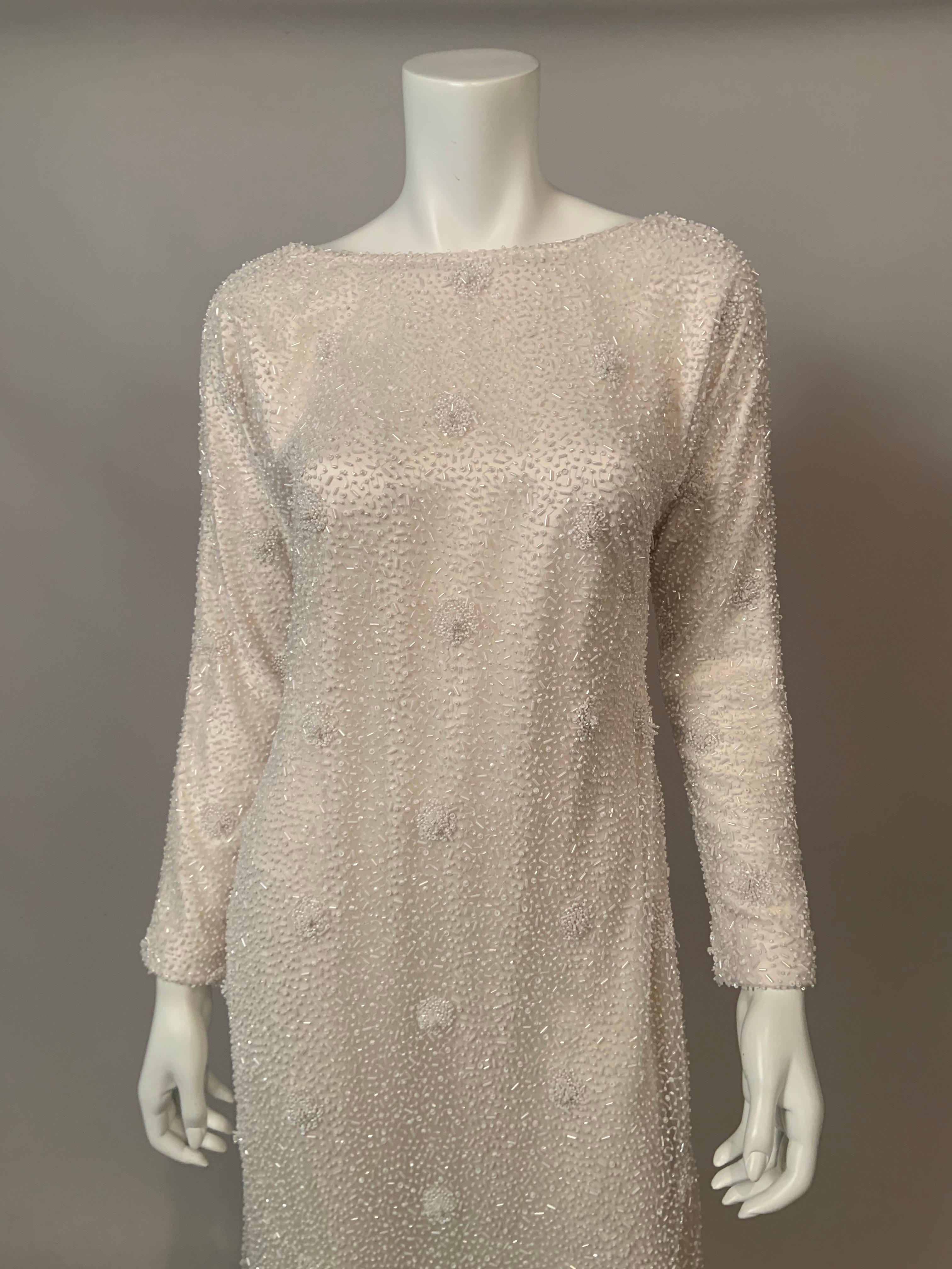 Naeem Khan a conçu cette magnifique robe avec des perles blanches sur un tulle transparent sur une doublure en charmeuse de soie blanche. Le perlage couvre l'ensemble de la robe avec des motifs floraux perlés tout au long de la robe. Le dos de la