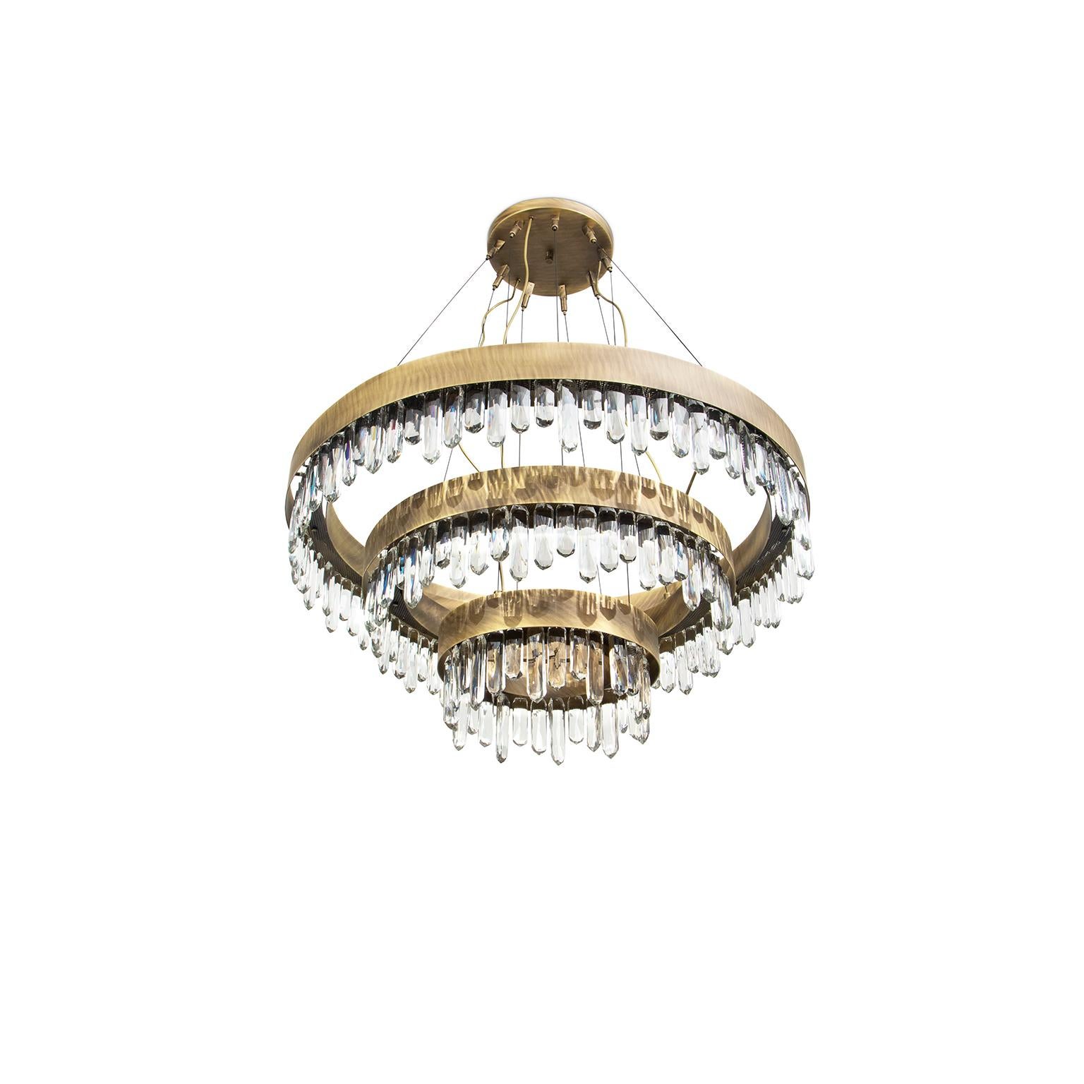 The allure of Mexico’s Giant Crystal Cave was the inspiration for NAICCA Chandelier, a round chandelier that represents the legend of crystal origins. The aged brushed brass structure and the Quartz crystal diffuser merge together to brighten any