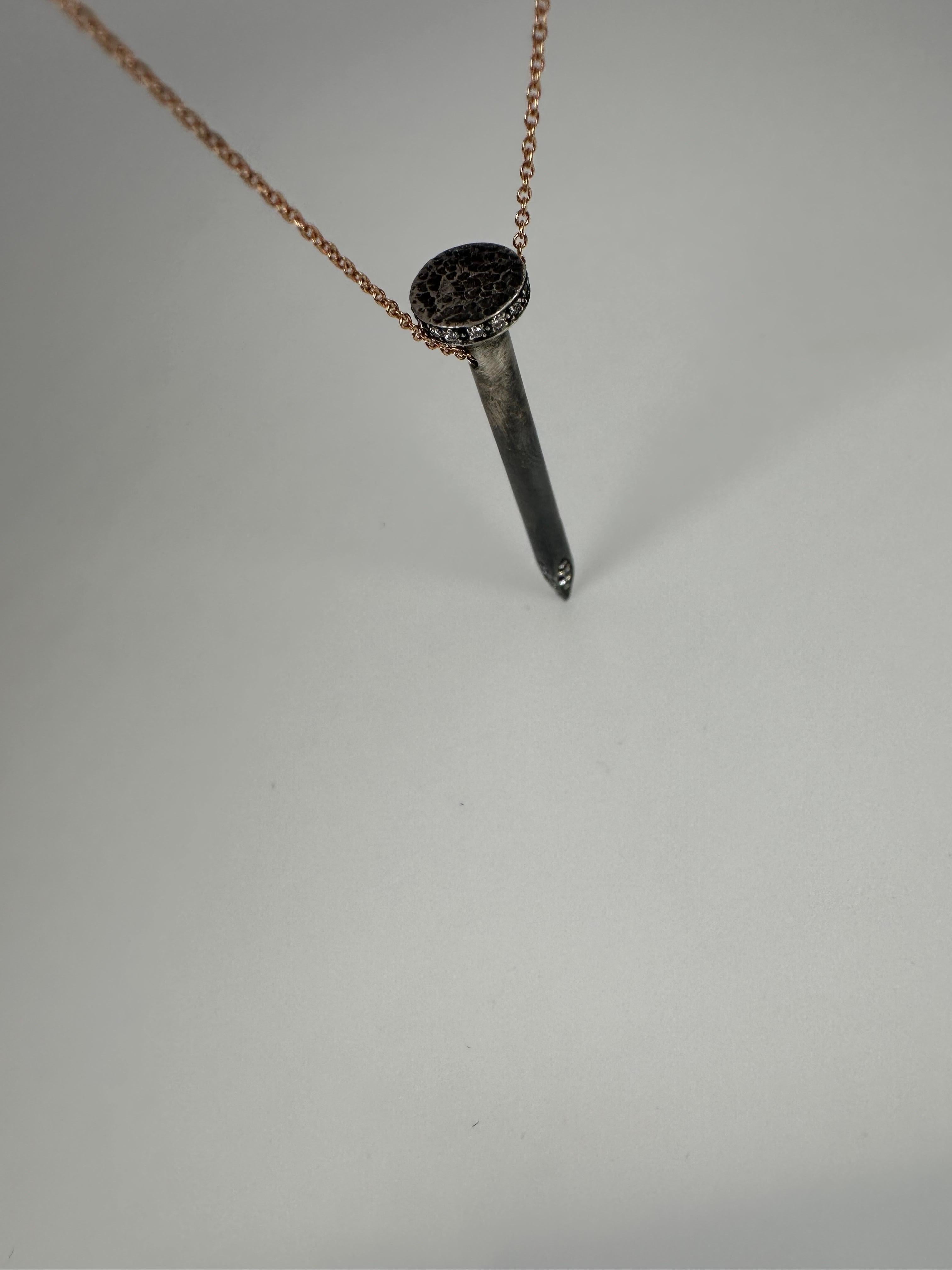 Extraordinary pendant necklace, the nail pendant is made with silver and black gold to resemble a real nail, set with fantastic quality diamonds and finished with 18KT chain. 

GOLD: 18KT gold chainn and 925 silver nail
NATURAL