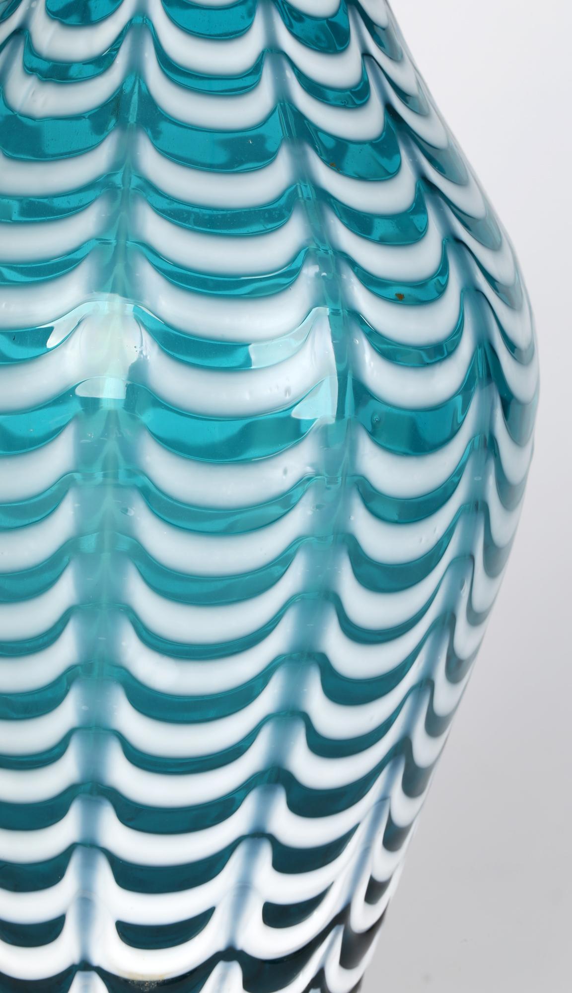 A large Nailsea Turquoise art glass vase with a combed white glass overlay in a feather style design and believed to date from the late 19th or early 20th century. This tall stylish blown glass vase has a fluted round bulbous shaped body with a