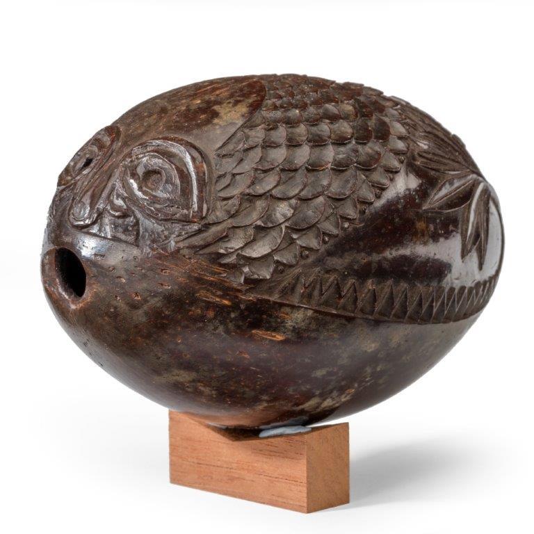 A naïve coconut shell “bugbear” powder flask carved as a fish with an open mouth surrounded by scales above a man hunting with a rifle and dogs, the underside plain, circa 1805. 

“Bugbear” coconut shell powder flasks
They were reputedly carved