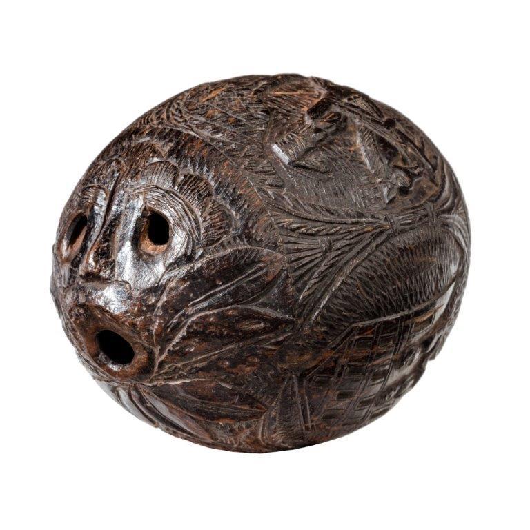 A naïve coconut shell “bugbear” powder flask with a pierced face at the end and four ovals showing, lovers before a mansion, a lady, a man and a cavalry officer, circa 1805.
