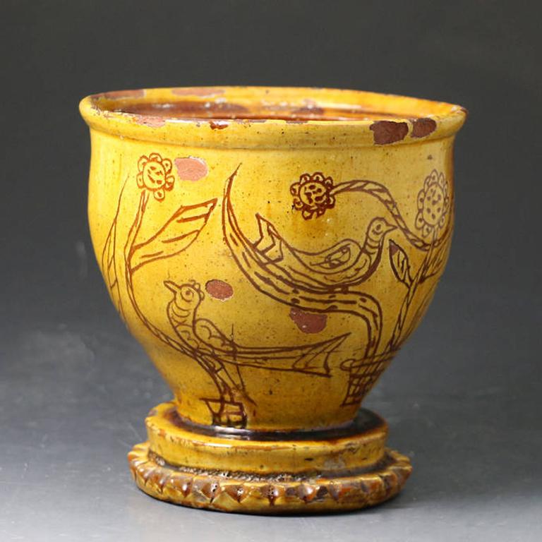 A naive country slipware earthenware pottery pot with charming graffito decoration of birds and leaves. 
It is likely that this piece would originally have a cover now lacking. 
Probably the work of the Fishley family of potters who were based in