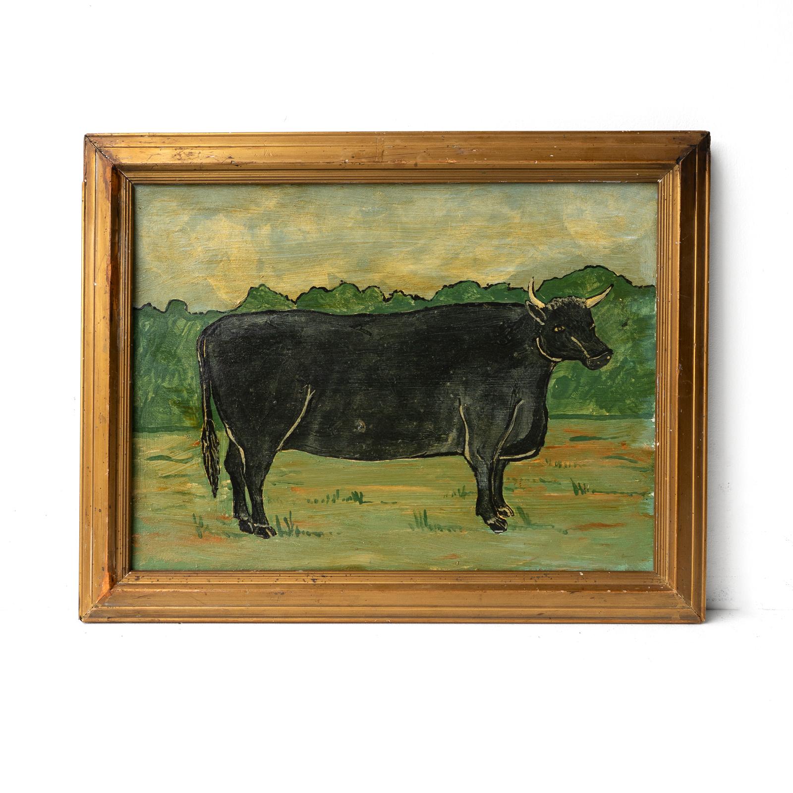 VINTAGE FRAMED PAINTING
Depicting a horned black cow standing in a field with a charming glint in its eye.

Painted in a naive folk art style.

Probably dating to the mid-20th Century, c 1930s-1960s period.

Framed in a simple gilt frame.

The