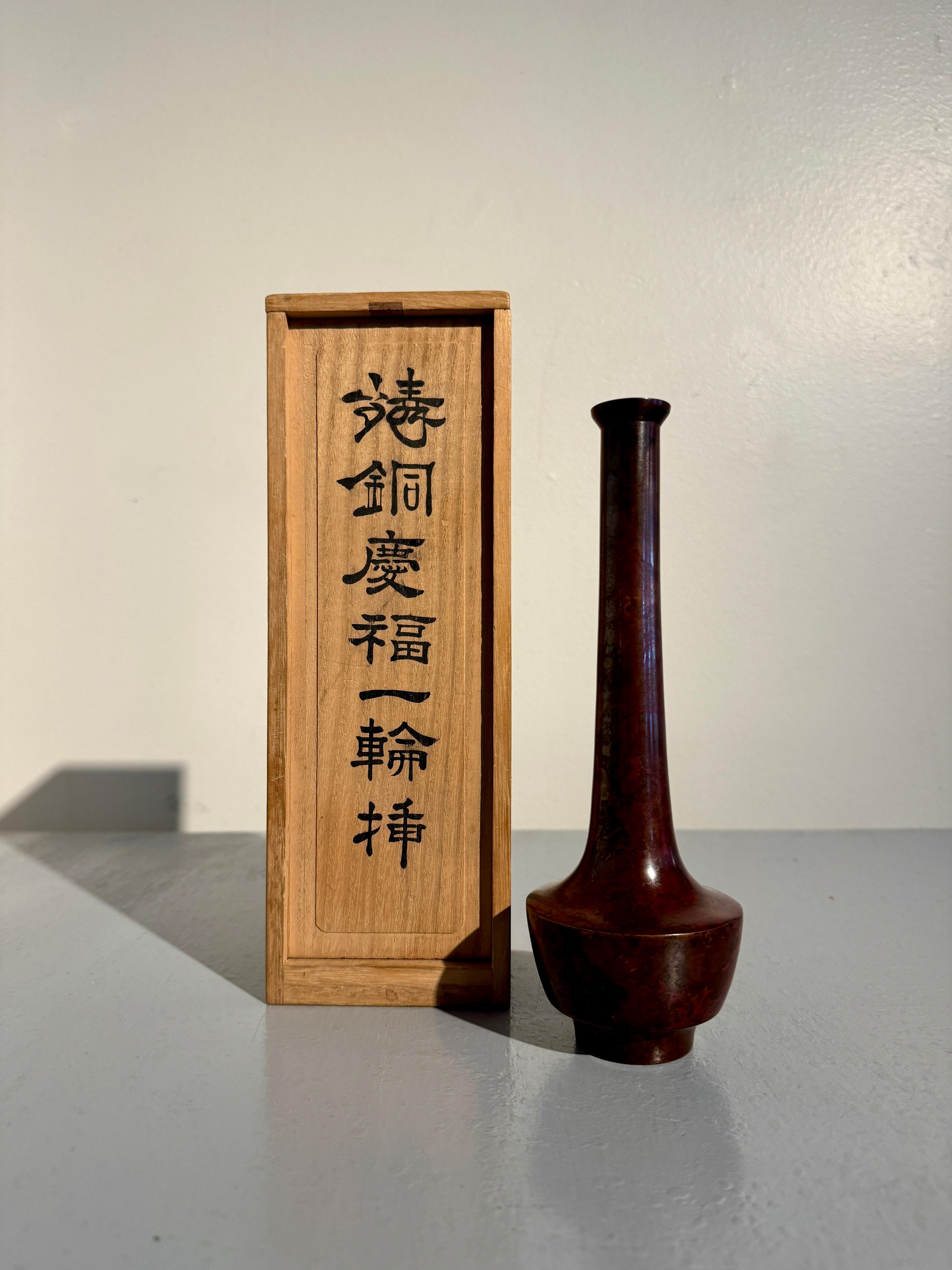 Eine elegante japanische Ikebana-Vase aus patinierter Bronze von Nakajima Yasumi II (1905 - 1986), um 1960, Osaka, Japan.

Die hohe Vase hat eine anmutige Form mit einem hohen runden Fuß, der einen becherförmigen Körper trägt, der zu einer scharfen,
