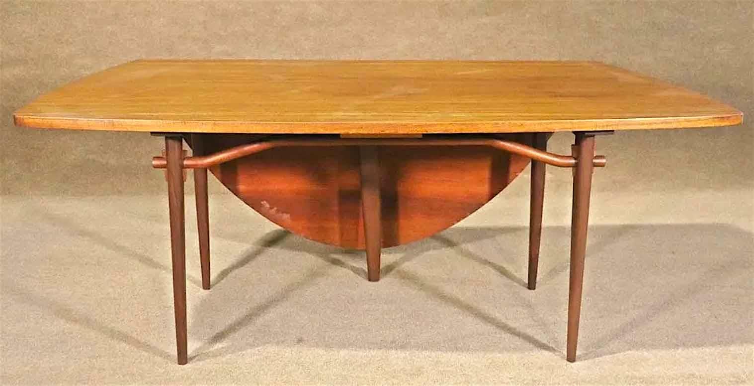 Mid-Century Modern dining table designed by George Nakashima for the “Origins” collection manufactured by Widdicomb Furniture, circa 1950s. Simple and elegant design features a free form table top with flowing walnut grains. Fifth leg slides out to
