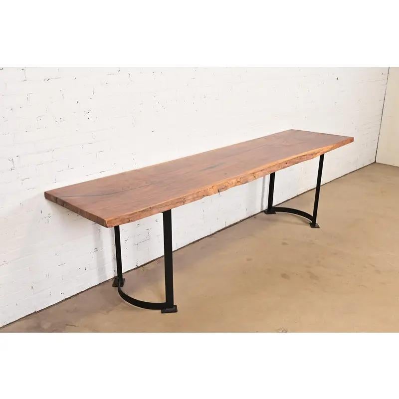 An exceptional Modern studio crafted monumental console table or harvest table

In the manner of George Nakashima

USA, Circa Late 20th Century

Gorgeous live edge solid walnut slab top, with iron pedestal legs.

Measures: 113.75