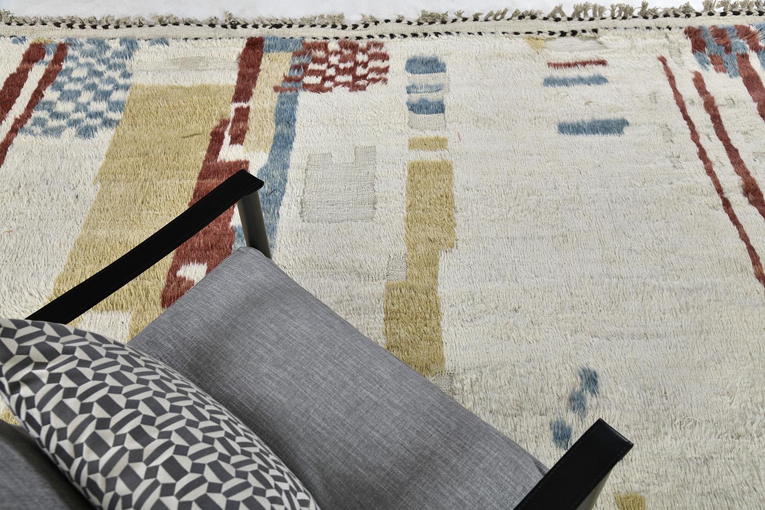 Nakhla is a natural earth-toned rug and a modern interpretation of the Moroccan world. These rugs irregular checkered of red and blue, khaki, and salt and pepper strokes an off-white field resemble the fibers of nature and their ability to be used