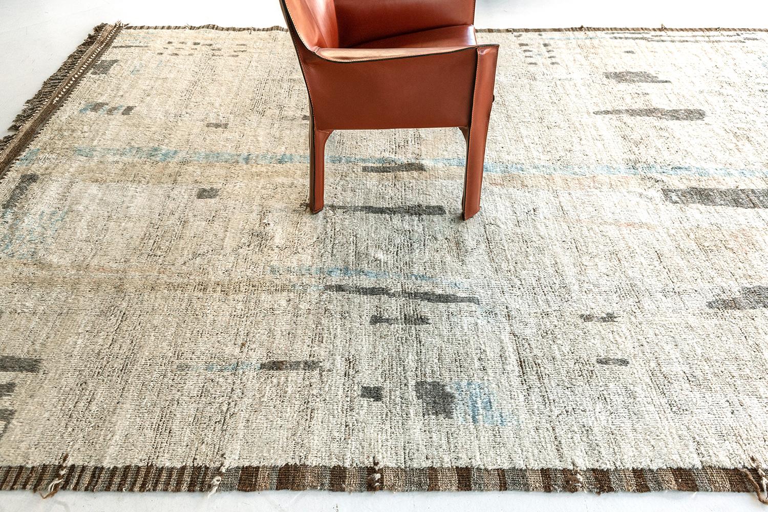 'Nakhla' is a natural earth toned rug and a modern interpretation of the Moroccan world. This rugs irregular ivory, khaki, blue, and salt and pepper strokes resembles the fibers of nature and their ability to be used for crafts such as cords and