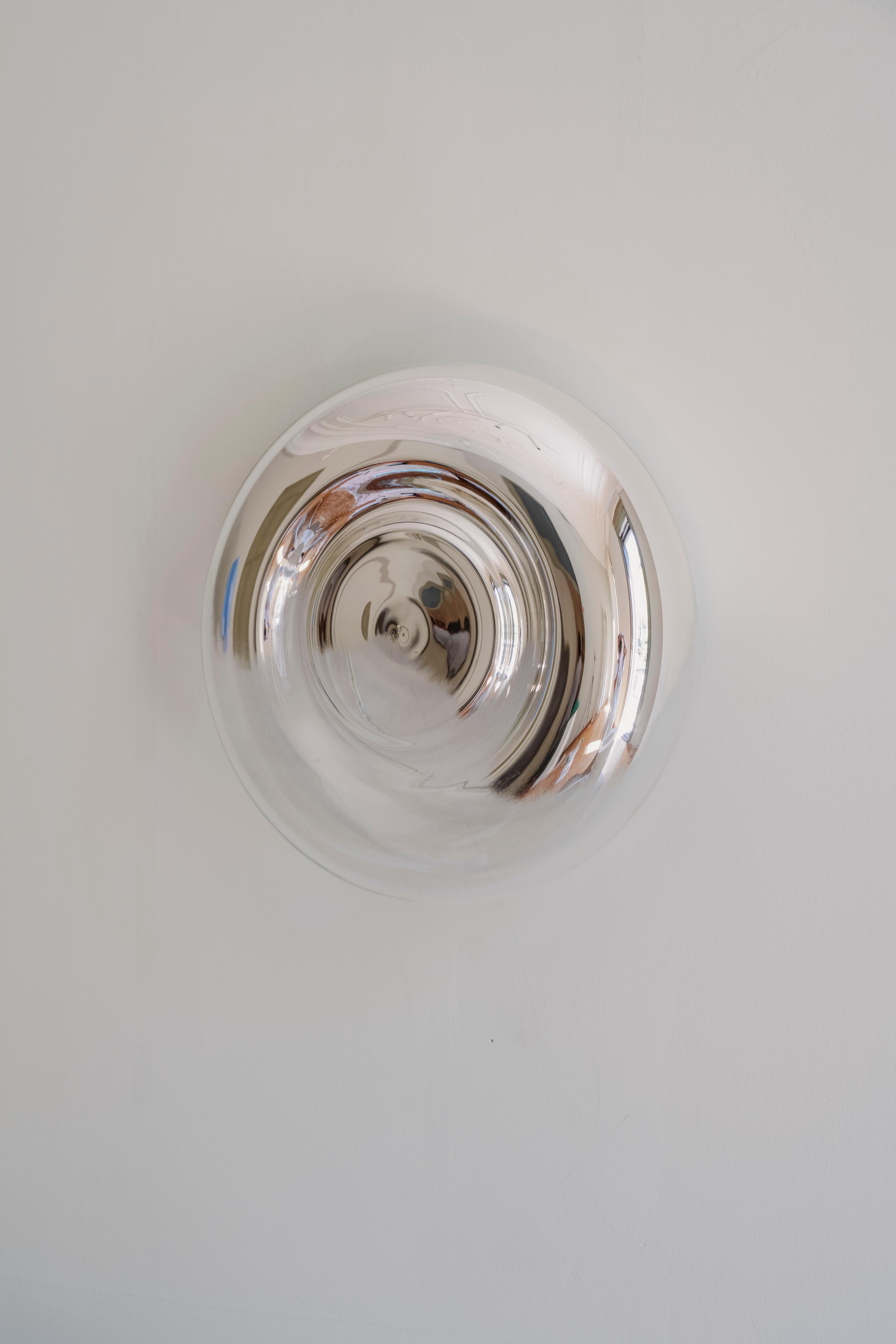 Näkki est un miroir mural rond fabriqué à la main en verre soufflé et plaqué argent selon des techniques traditionnelles. Cette pièce en édition limitée est le fruit d'une collaboration entre la designer suédoise Sanna Völker, basée à Barcelone, et