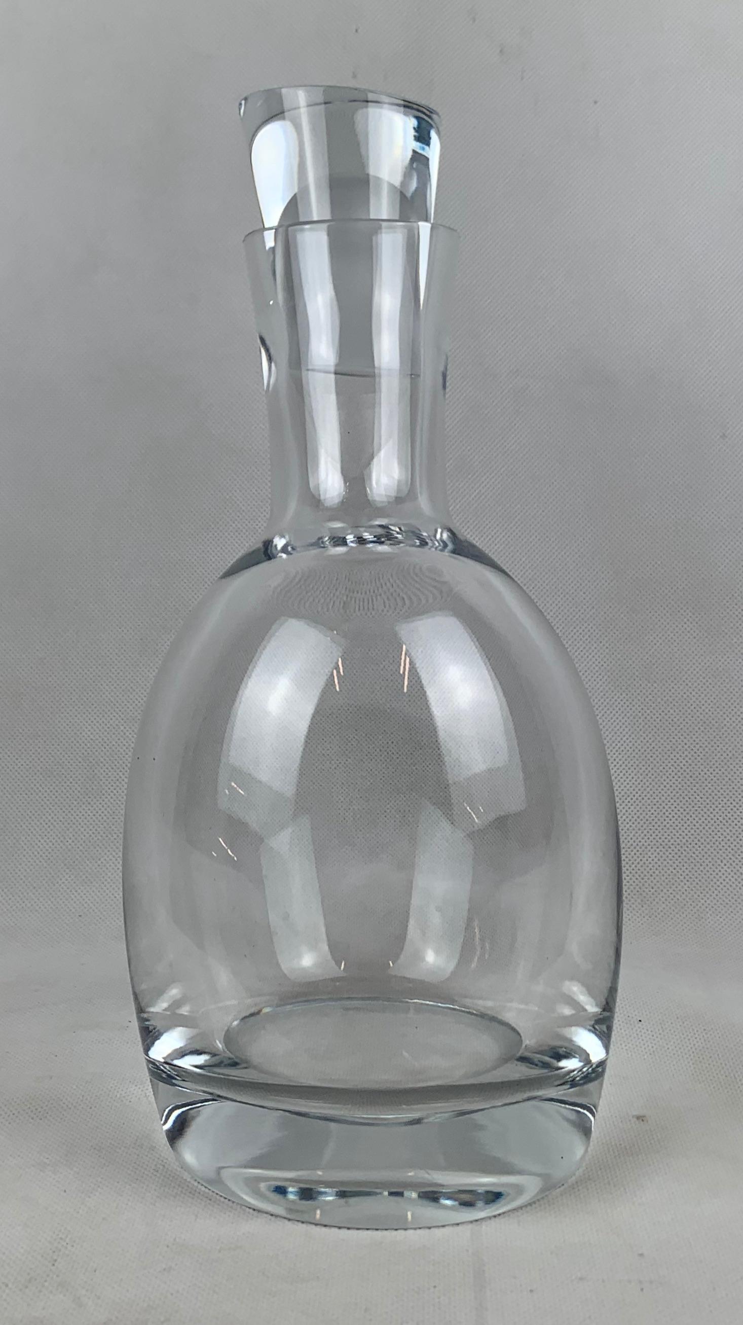 Nambé clear crystal spirits decanter. Twentieth century assymetrical design. The design is unusual but very stable due to the thick counter weighted base. The stopper itself is a marvel made from heavy thick glass, but fits snugly into the decanter