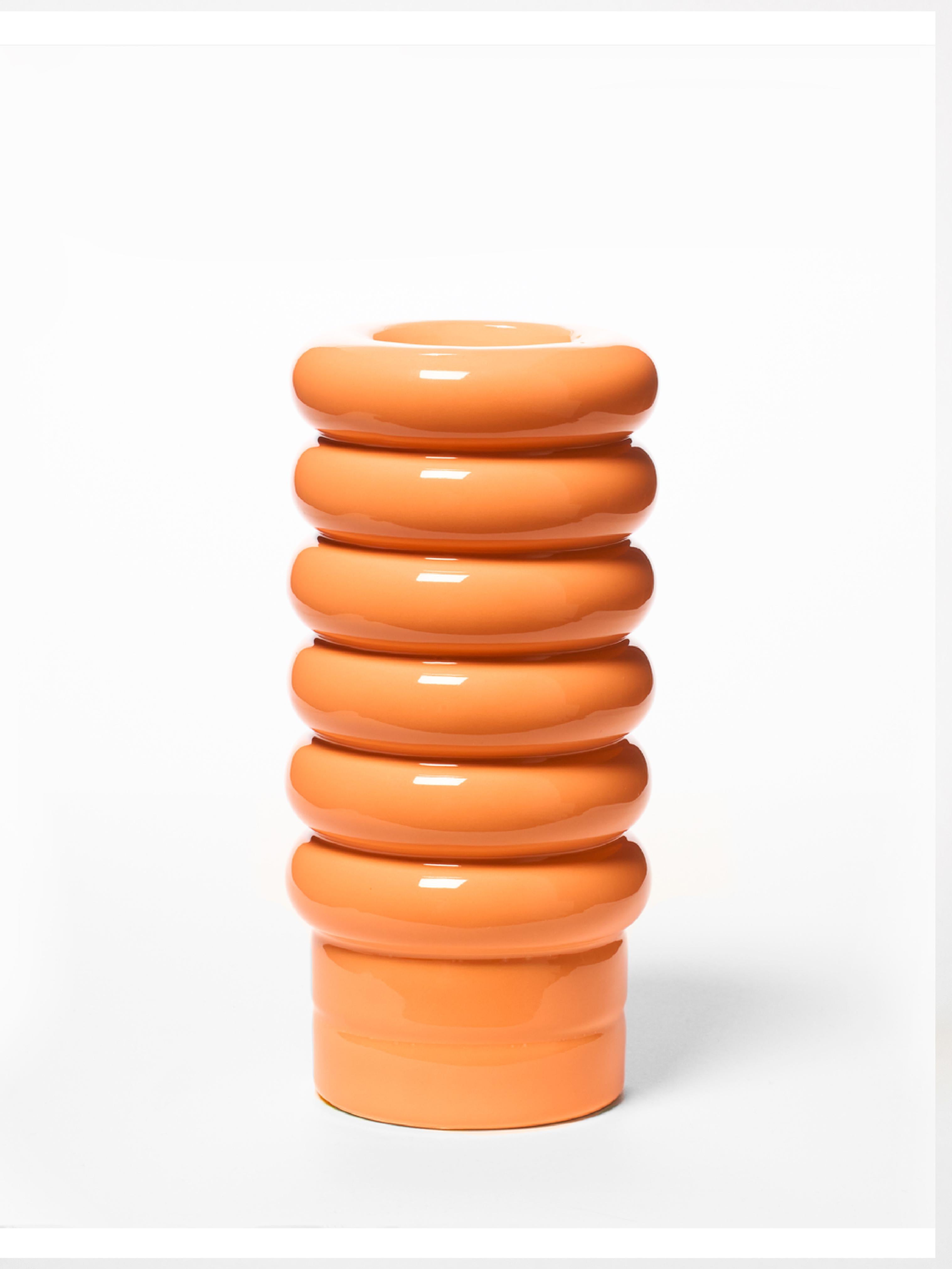 A small vase with a unique form composed of six pretzels and a contrasting base. The NANA vase beautifully displays any bouquet, its beauty accentuated by the vase's striking color. Placing a ceramic ball of any color on top of the NANA allows for