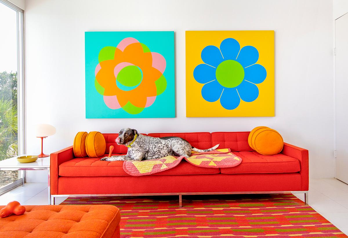 Happy by Nancy Baron is a 15 x 22 inch archival pigment print, available in an edition of 10. This photograph features a pointer/pit mix laying on a red couch with mid century modern furniture. The house in this photograph was designed by Donald
