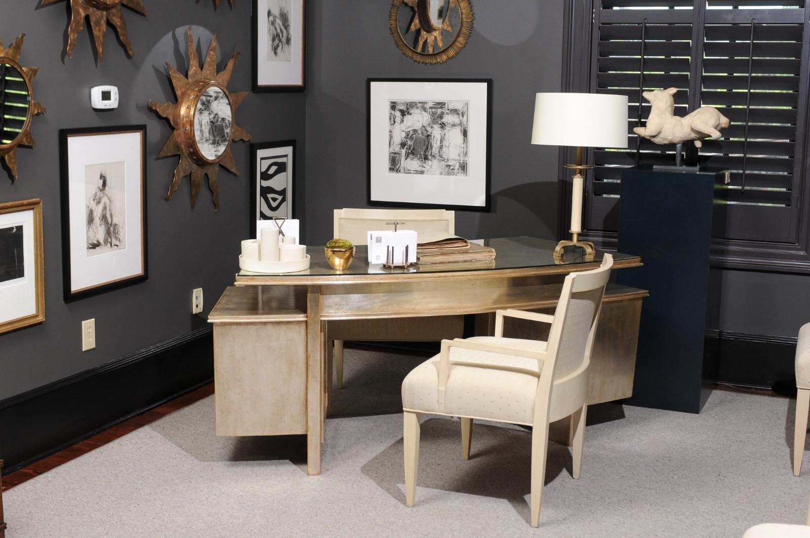 Nancy Corzine concave silver gilt writing desk with a custom glass top in the Art Deco style.
The raised center desk features two lower side console tables and all fit within the concave arc of the desk. Beautiful silver gilt gives a soft