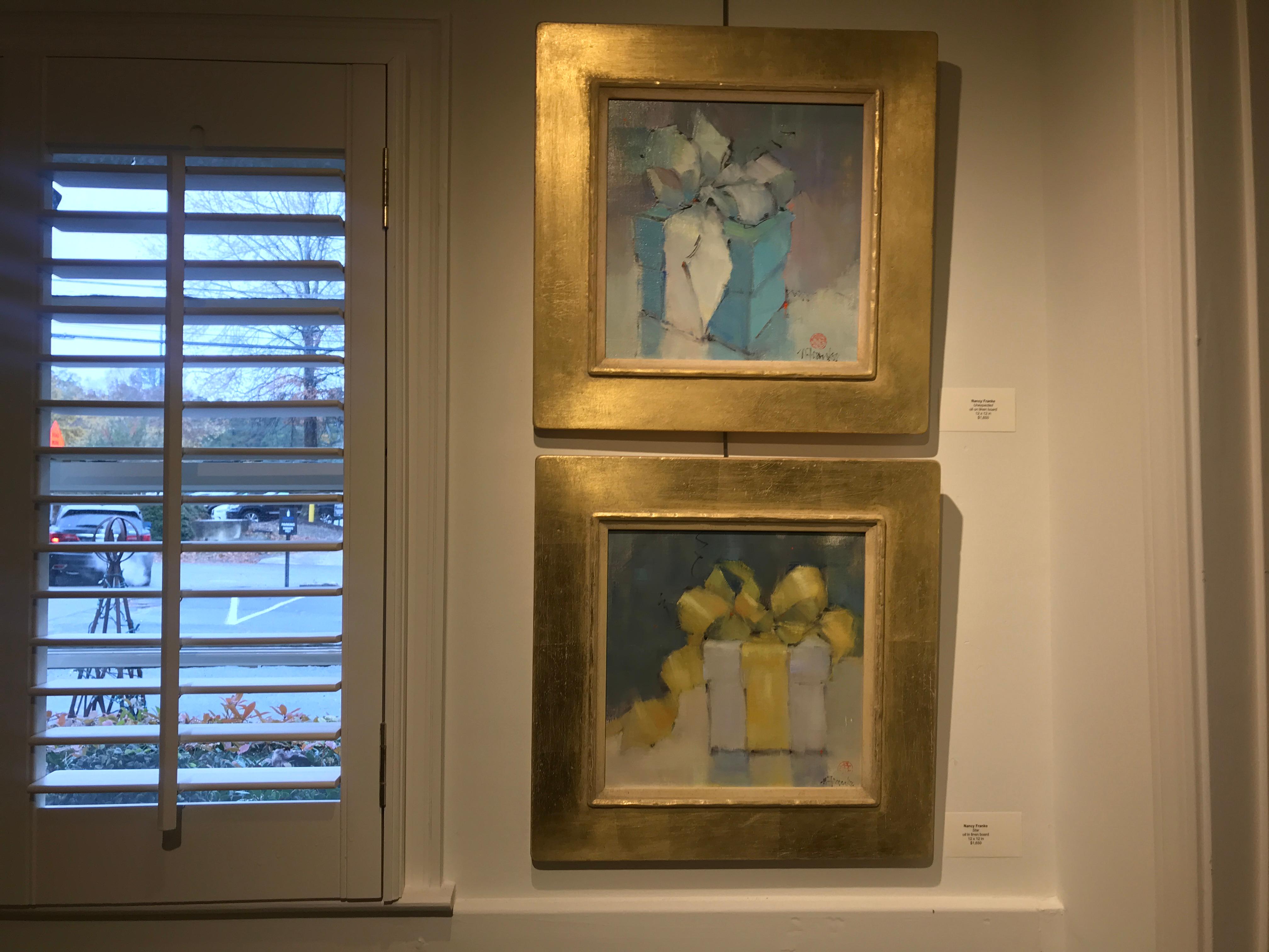 'Unexpected' is a small framed Impressionist oil on linen board painting created by American artist Nancy Franke in 2018. Set inside a handmade frame finished with 14k gold, the painting depicts a blue gift-wrapped box adorned with a delicate white