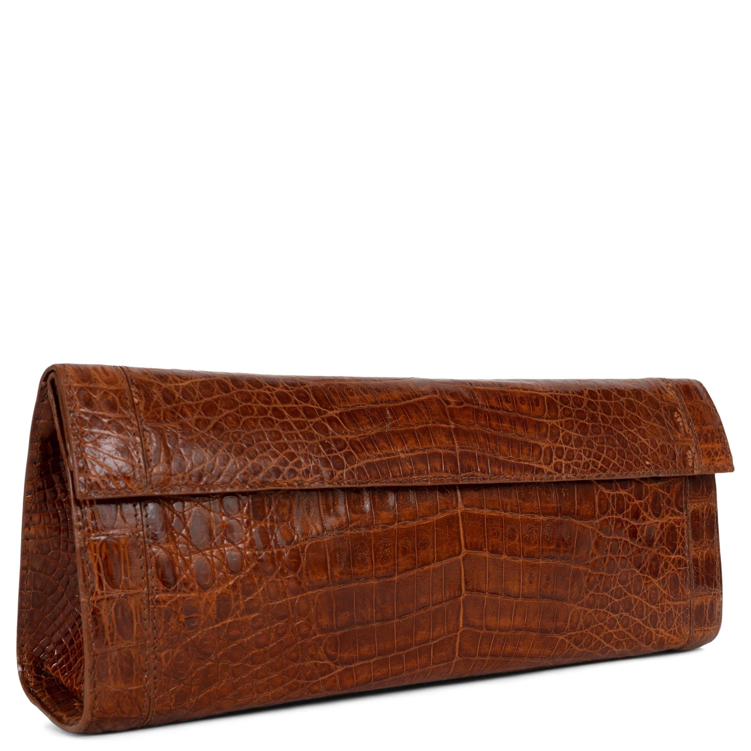 This 100% authentic Nancy Gonzalez Gotham Small clutch in brown shiny caiman croc showcases timeless sophistication with its sleek envelope silhouette. Featuring a magnetic snap flap closure, it opens to a beige suede-lined interior with an open