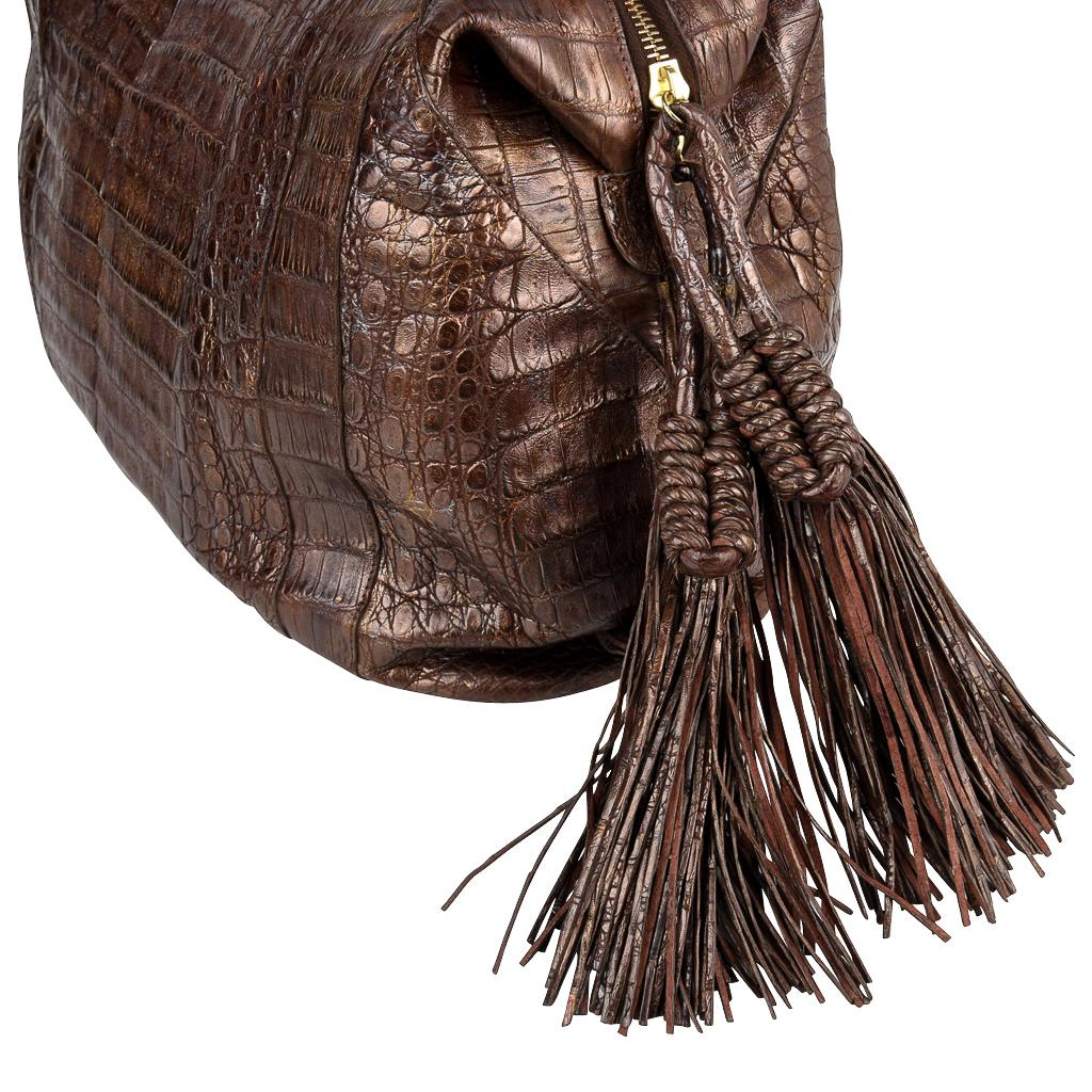 Mightychic offers a roomy brown Nancy Gonzalez crocodile bag with a gold iridescent overtone. 
Roomy zip top satchel with rolled skin handles that can be worn on the shoulder or hand held. 
Large lush leather ring tassels on either side of the