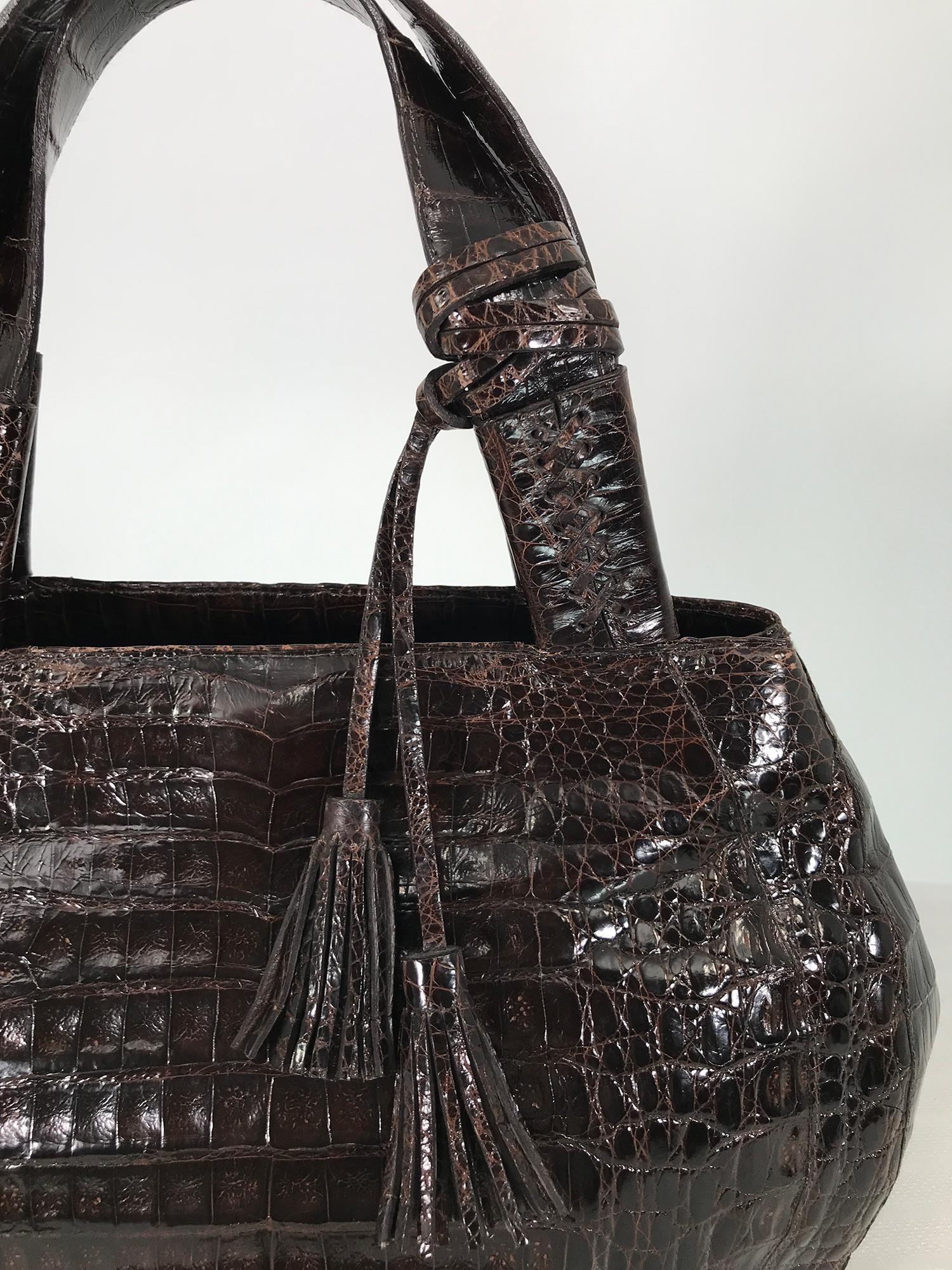 Nancy Gonzalez large dark brown crocodile double handle handbag. This beautiful bag is perfect for dressy to casual wear, two wide handles are detailed with cross stitching. The oval shape bag closes at the top with hidden magnetic closures, and an