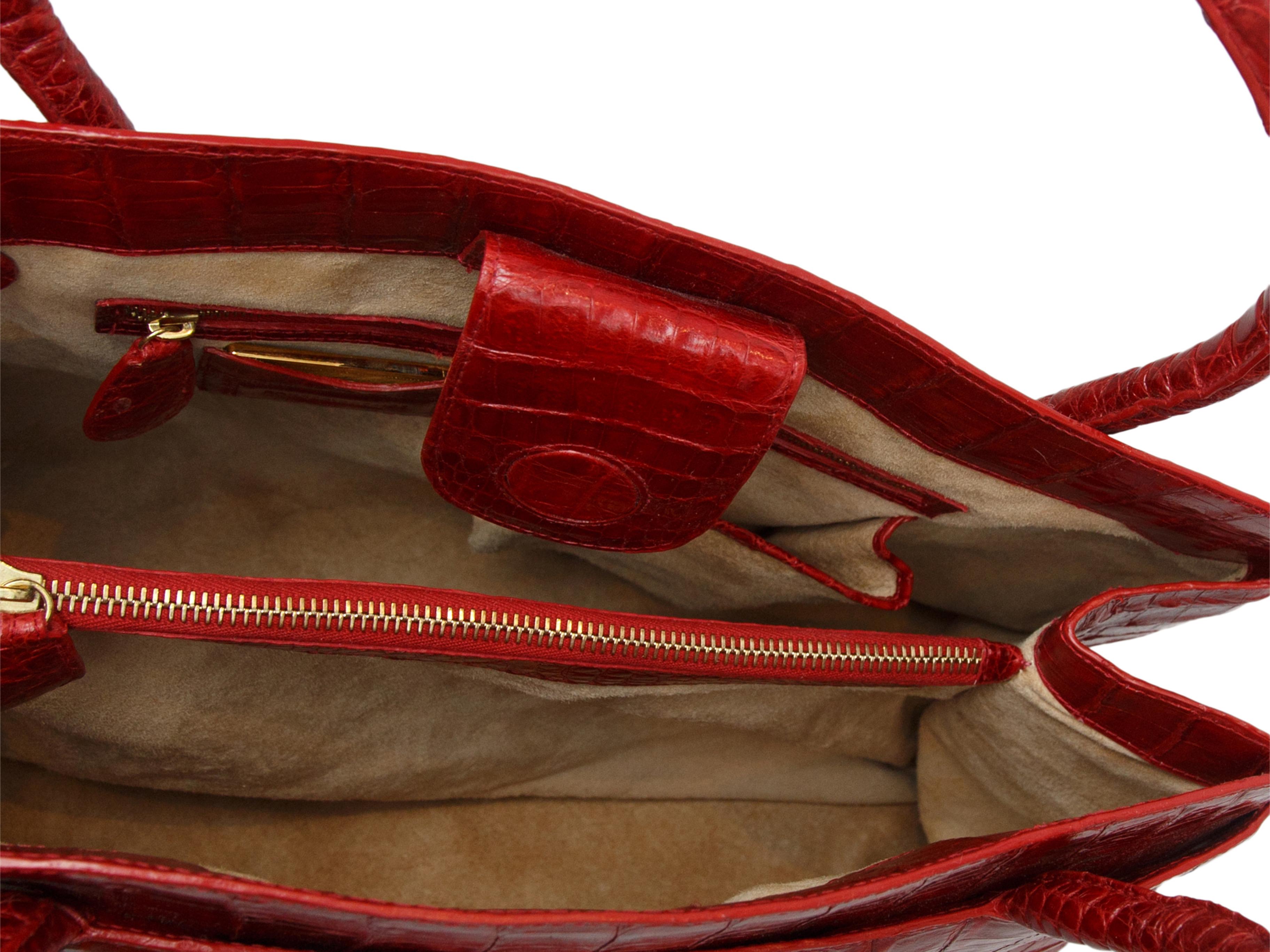Product details: Red crocodile handbag by Nancy Gonzalez. Dual top handles. Interior zip pocket. Magnetic closure at top. 14