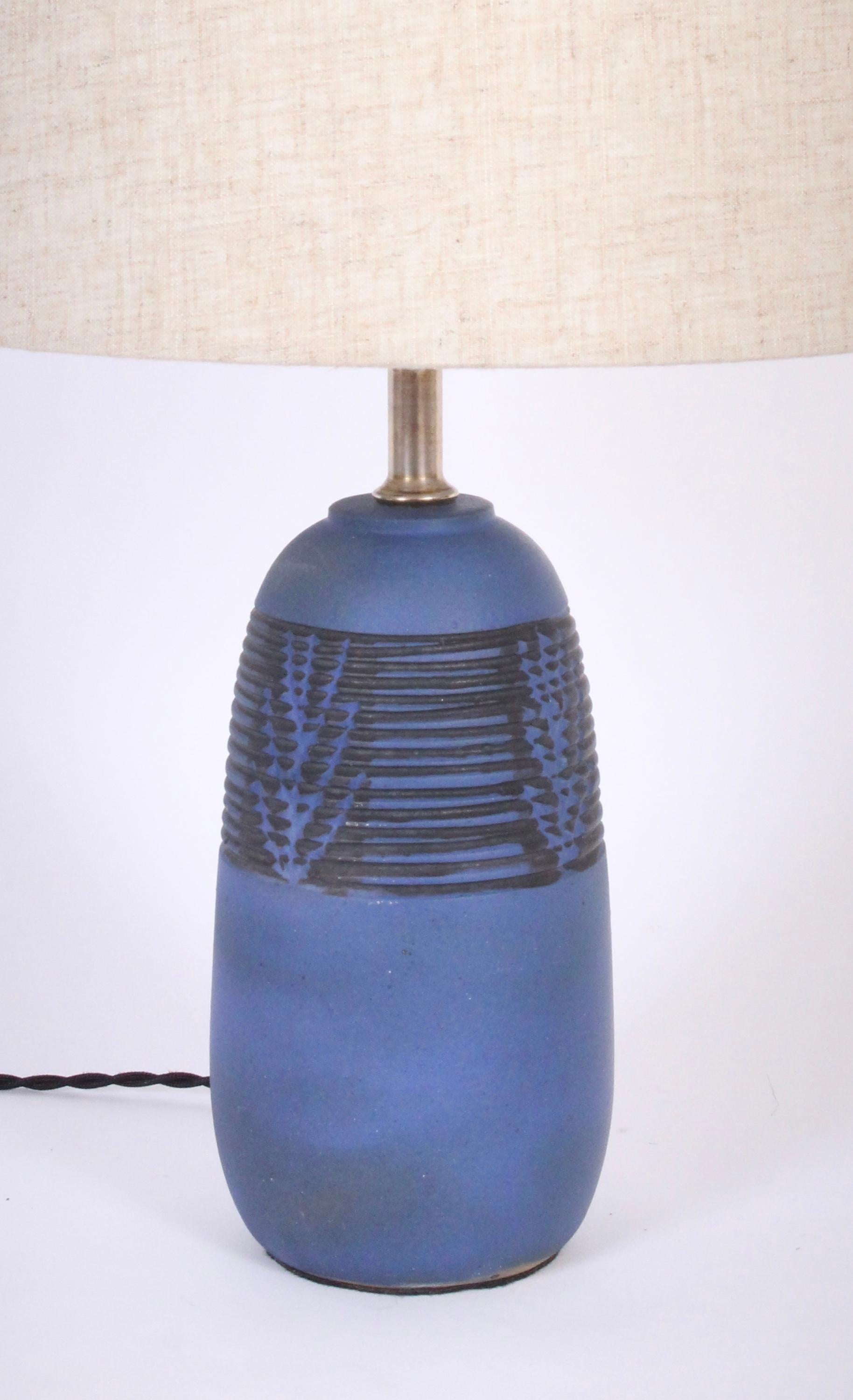 Smaller Nancy Wickham Boyd for Design Technics carved blue ceramic bedside lamp with black detail. Handcrafted blue matte glazed form accented with applied Black paint. Small footprint. 13H to socket. Ceramic 8.5H. Shade shown for display only (9H x