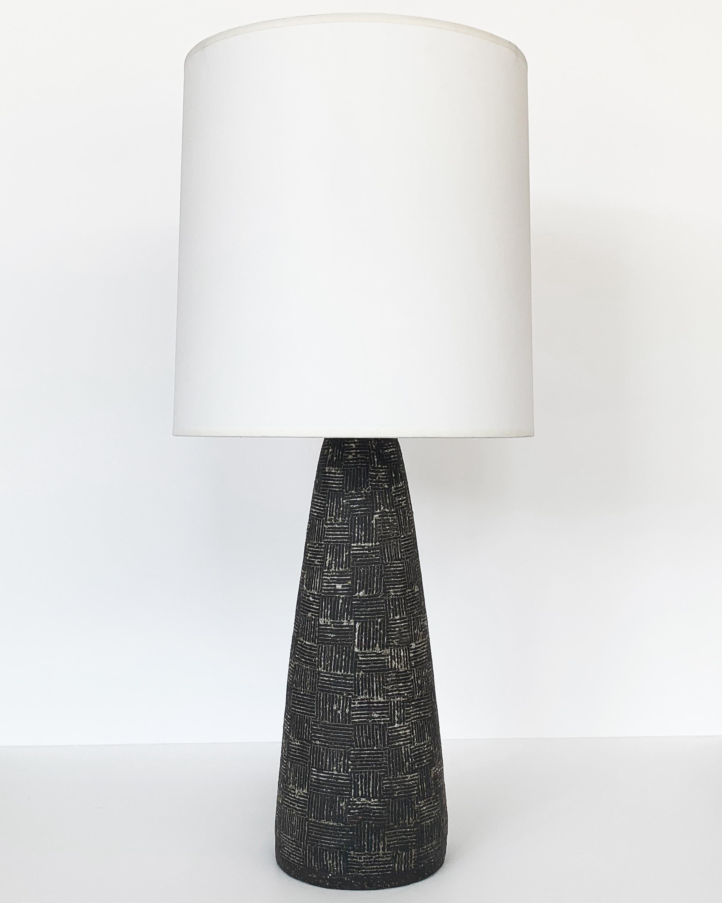 A midcentury ceramic table lamp in a conical form with a textured surface by Nancy Wickham, circa 1950s. Dark grayish brown stoneware with a cross hatched / basket weave design that has been filled in with a white glaze. The carved surface