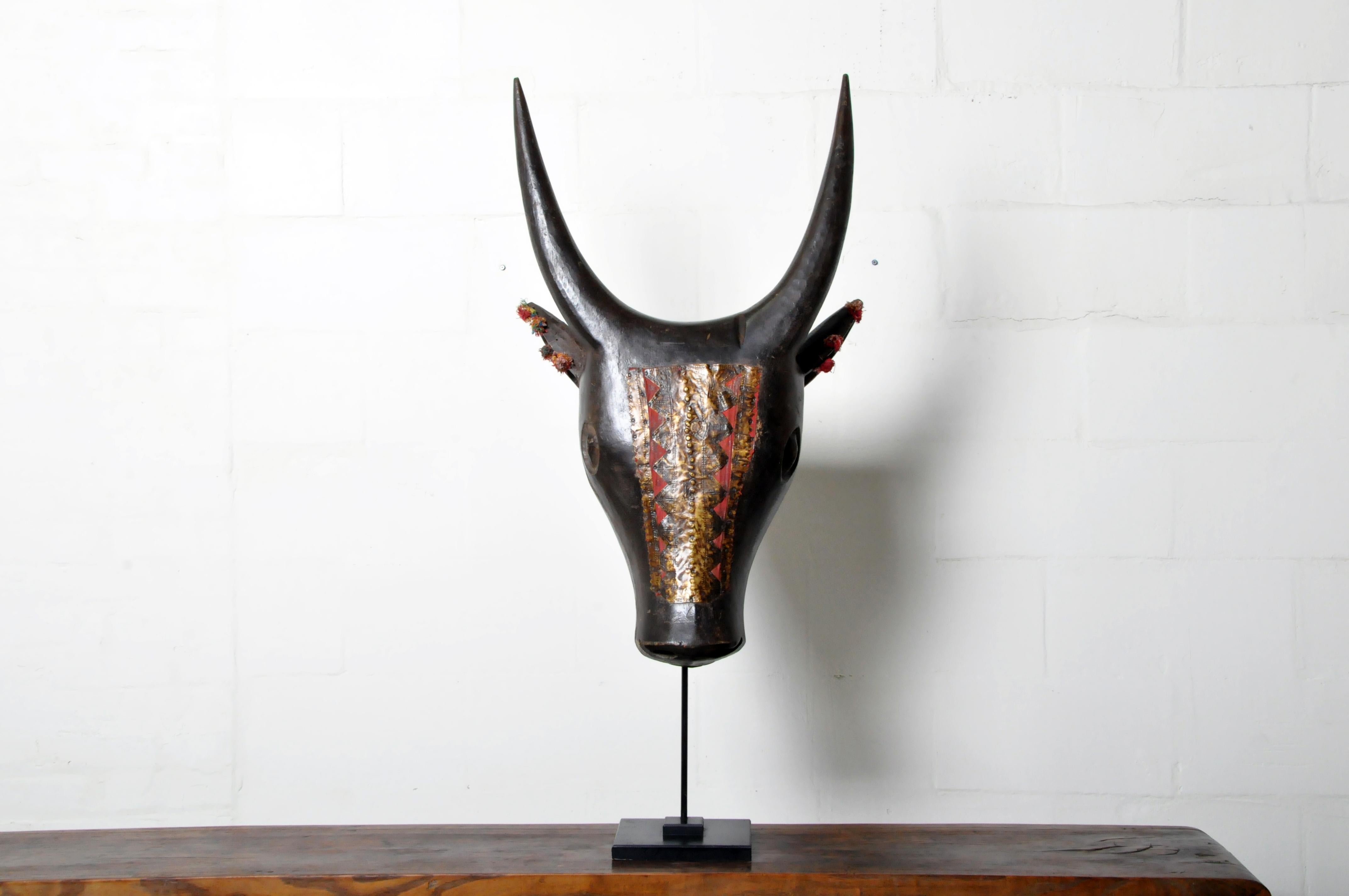 An Indian vintage Nandi bull sculpture from the mid 20th century, with carved motifs, dark patina, and metal adornment. Carved in India during the mid 20th century, this carved wooden sculpture features Nandi, son of the sage Shilada. Depicted as a