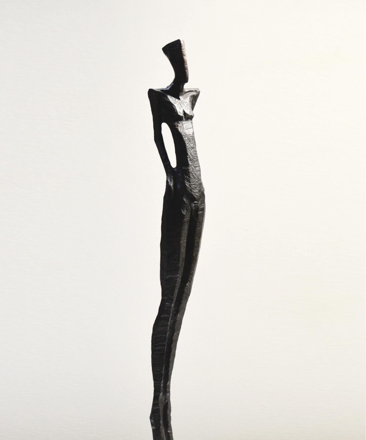 Antonio III is a tall, elegant bronze sculpture of a human figure.  

Nando Kallweit is a German sculptor working in bronze and oak.  Kallweit carves the original piece from a piece of oak using a chainsaw.  The oak marque is then used to create a