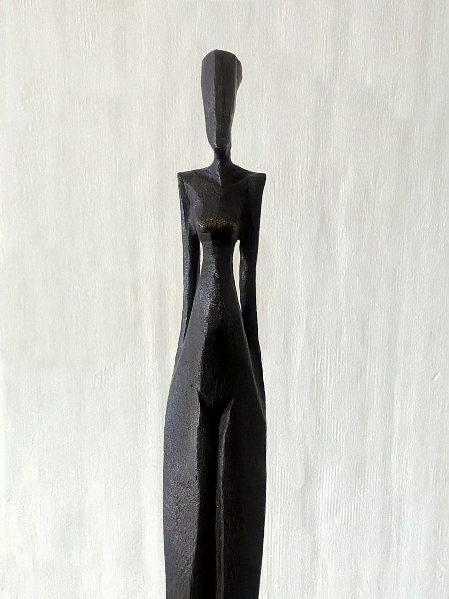 Kathy is a tall, elegant bronze sculpture of a human figure.  

Nando Kallweit is a German sculptor working in bronze and oak.  Kallweit carves the original piece from a piece of oak using a chainsaw.  The oak marque is then used to create a cavity