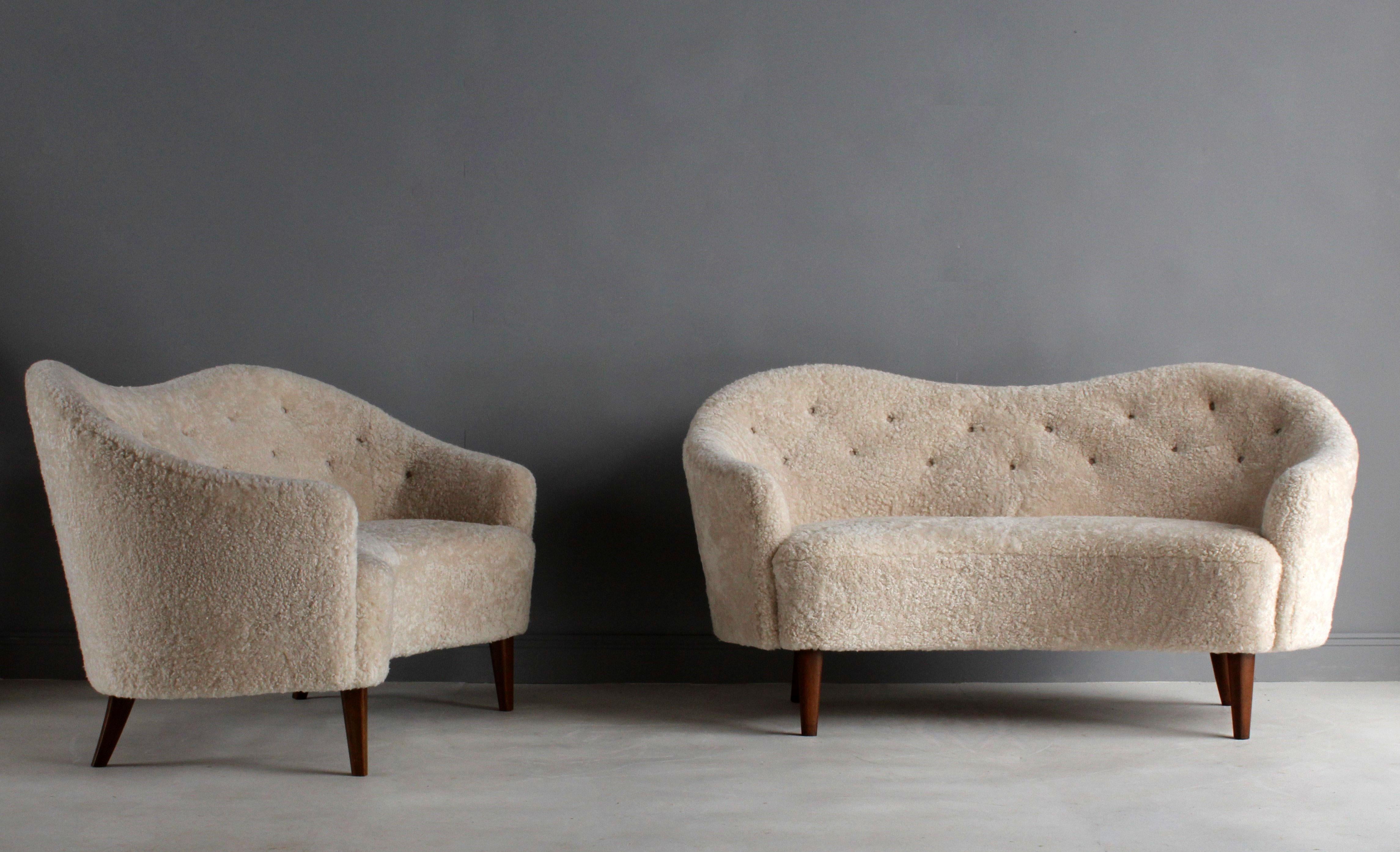 A pair of sofas/love seats attributed to Nanna Ditzel. Soft organic forms are further enhanced by the brand-new, authentic light beige/grey sheepskin upholstery. Mounted on stained beech legs.

The last image illustrates a pair of sofas documented