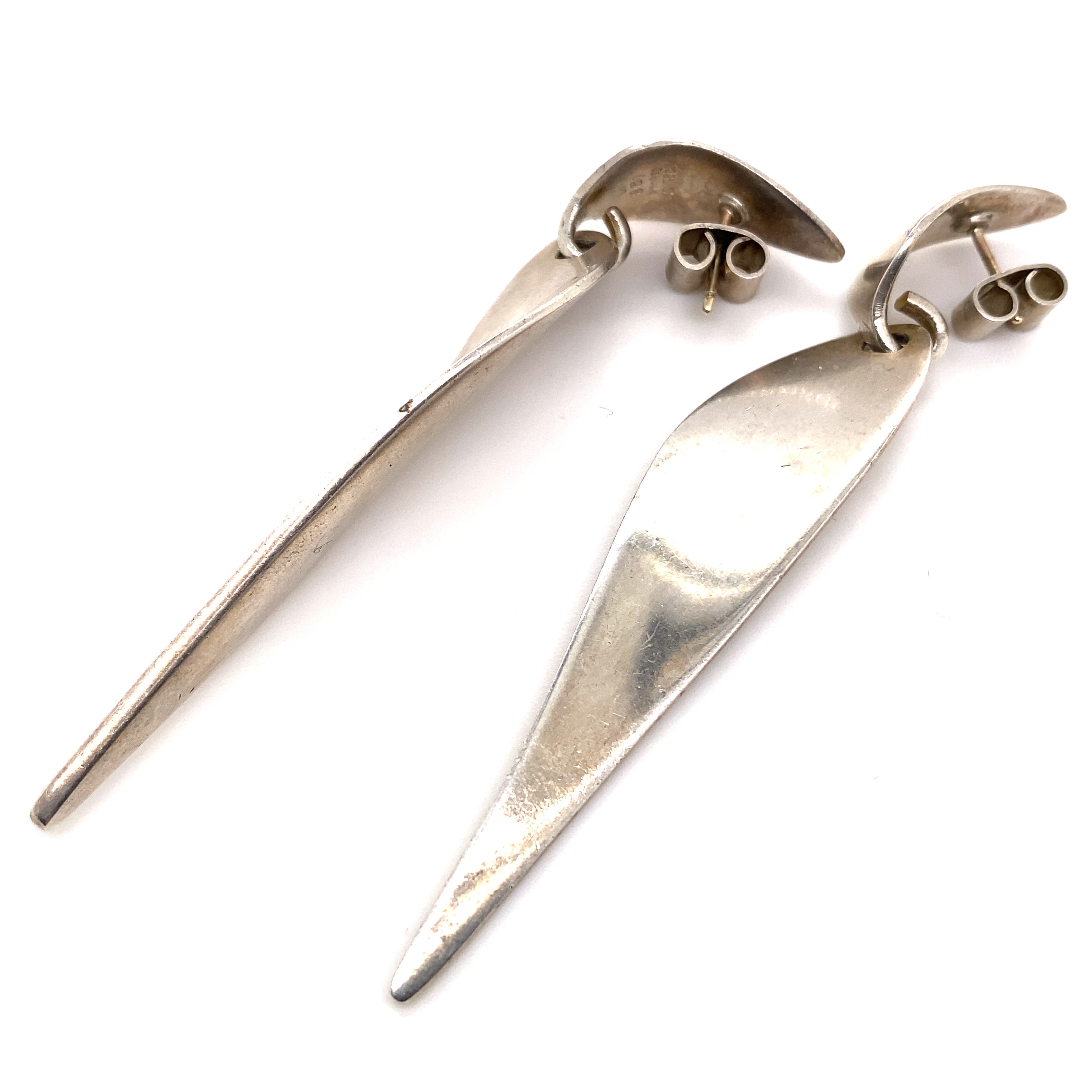A pair of Nanna Ditzel for Georg Jensen sterling silver no 128a drop earrings, circa 1968

Comprised of an elegant oval tear drop atop a curved and undulating silver shard, the two components are perfectly articulated and follow the line of the neck